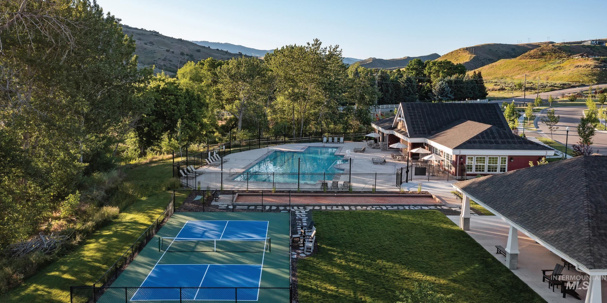 View of tennis court with a patio, a mountain view, and a community pool