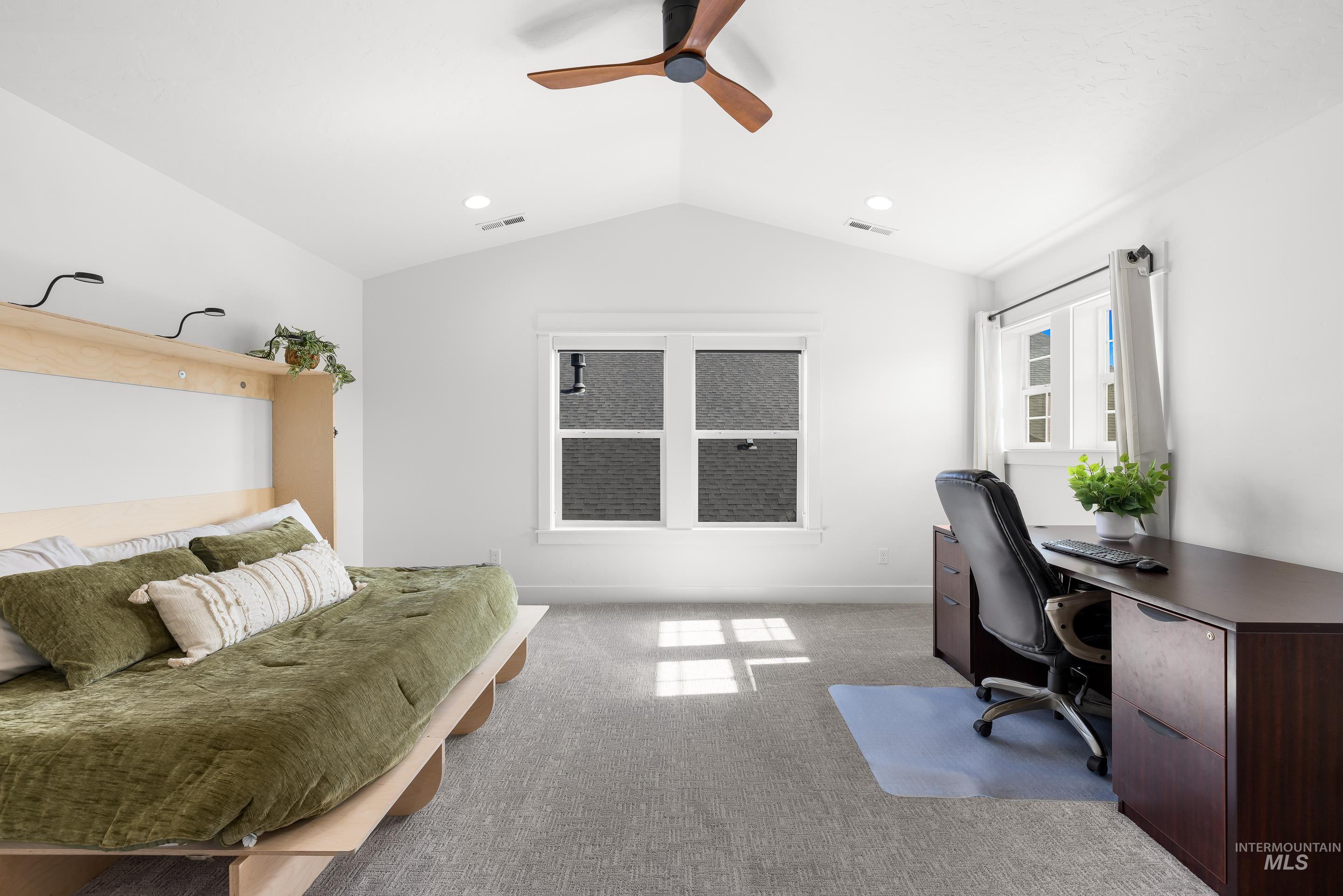 Carpeted office space with ceiling fan and vaulted ceiling