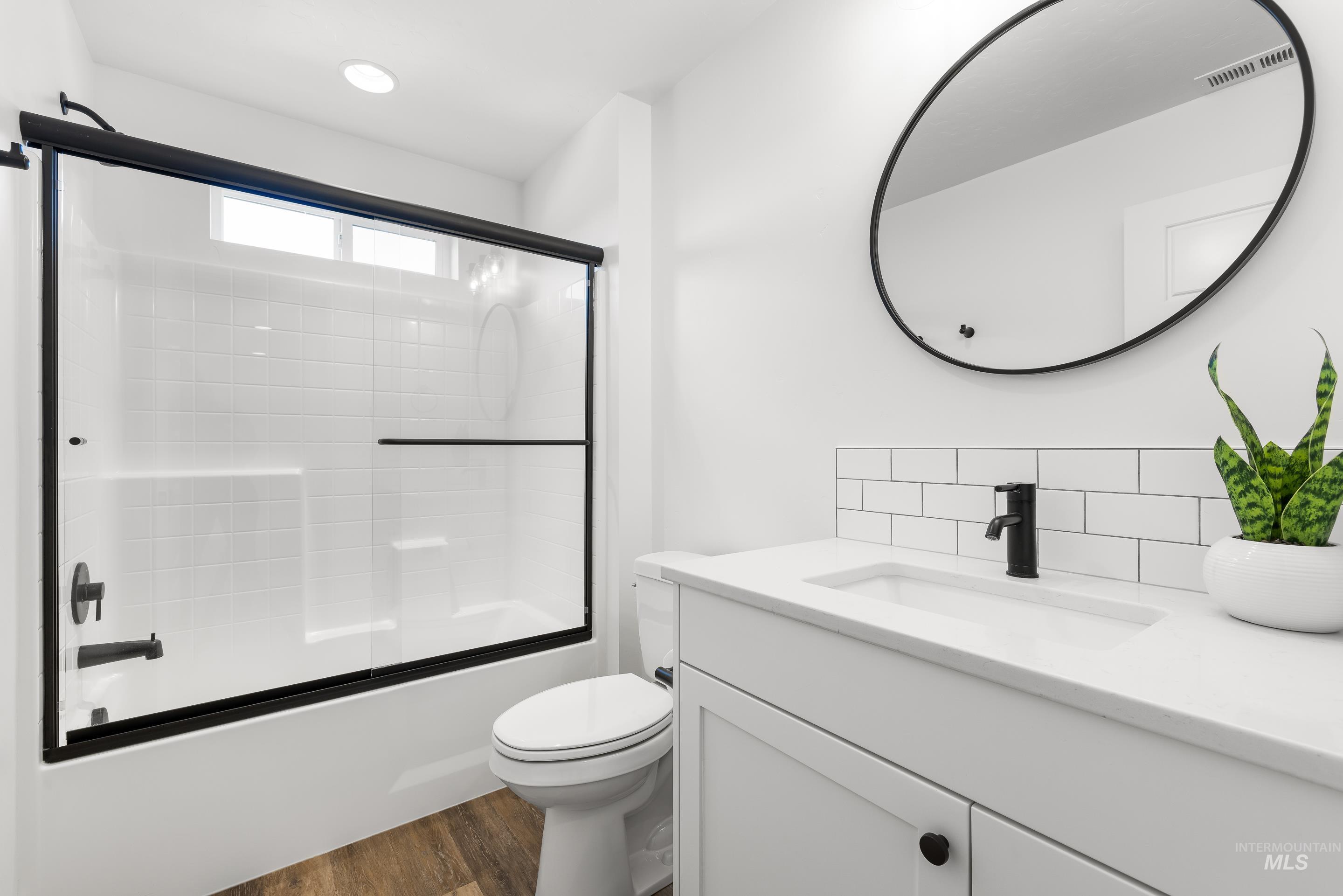 Bathroom with vanity, bath / shower combo with glass door, and dark wood-style floors