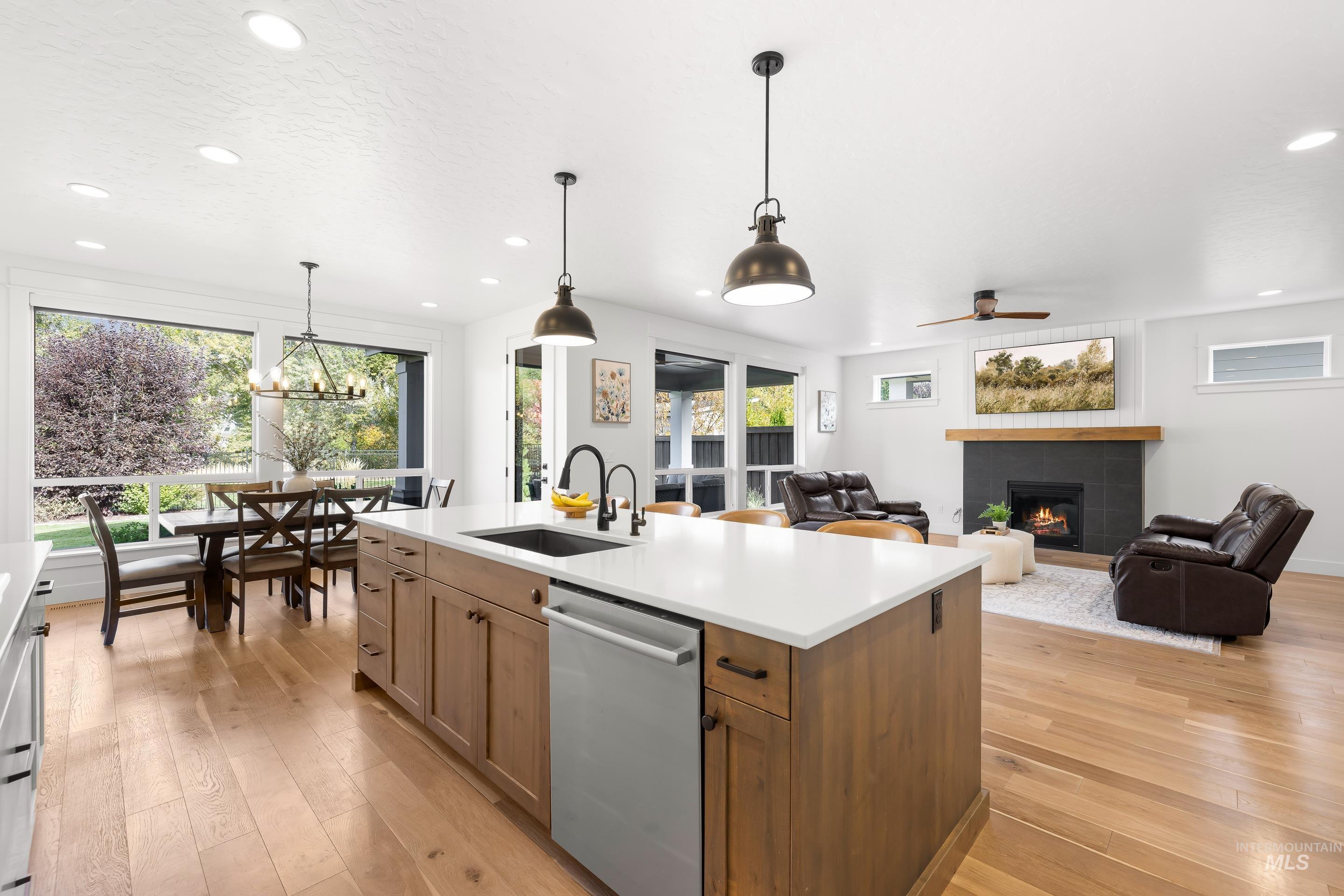 Kitchen with pendant lighting, a tile fireplace, stainless steel dishwasher, recessed lighting, and light wood-style floors