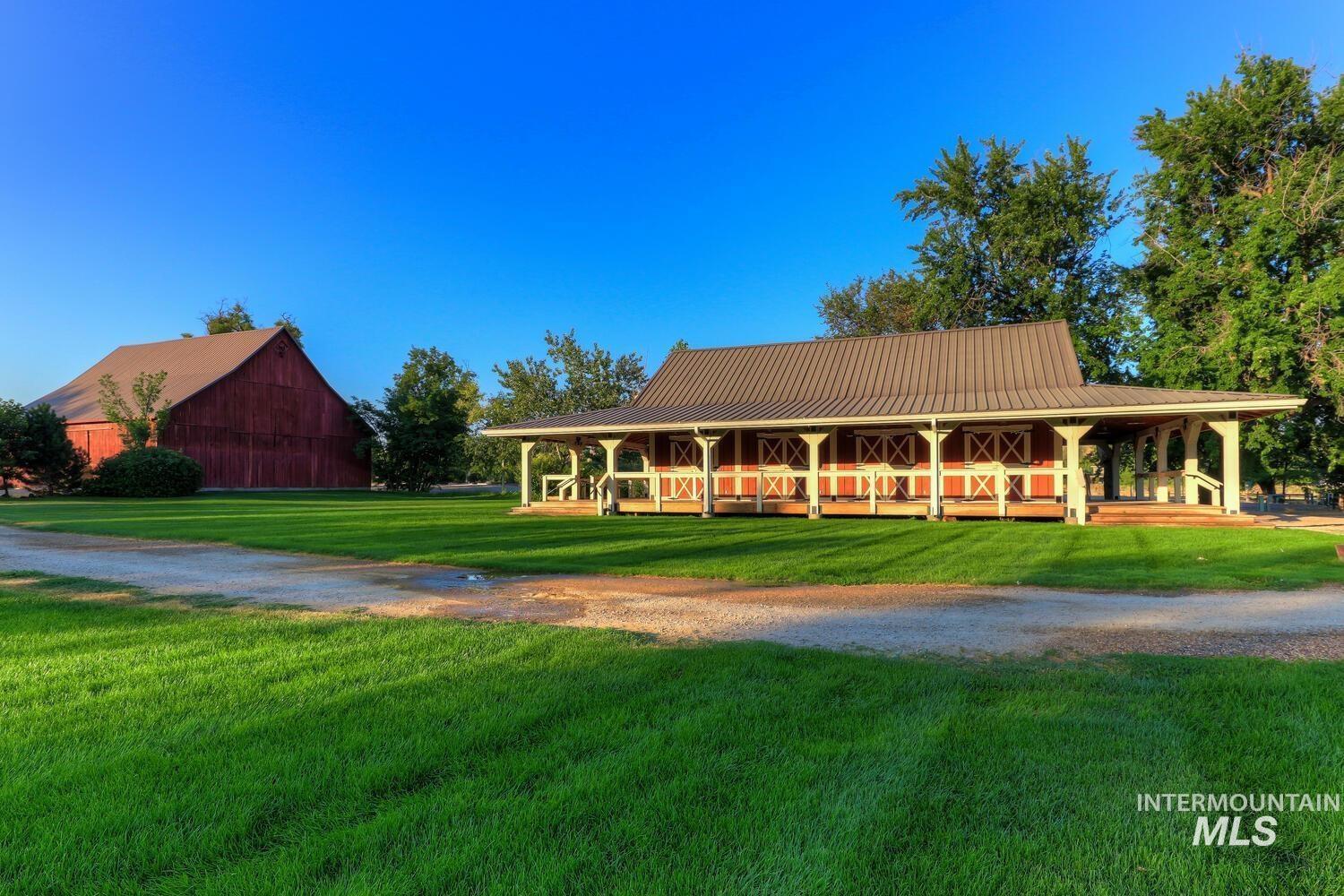 Farmhouse featuring a porch, a barn, a front lawn, and a metal roof