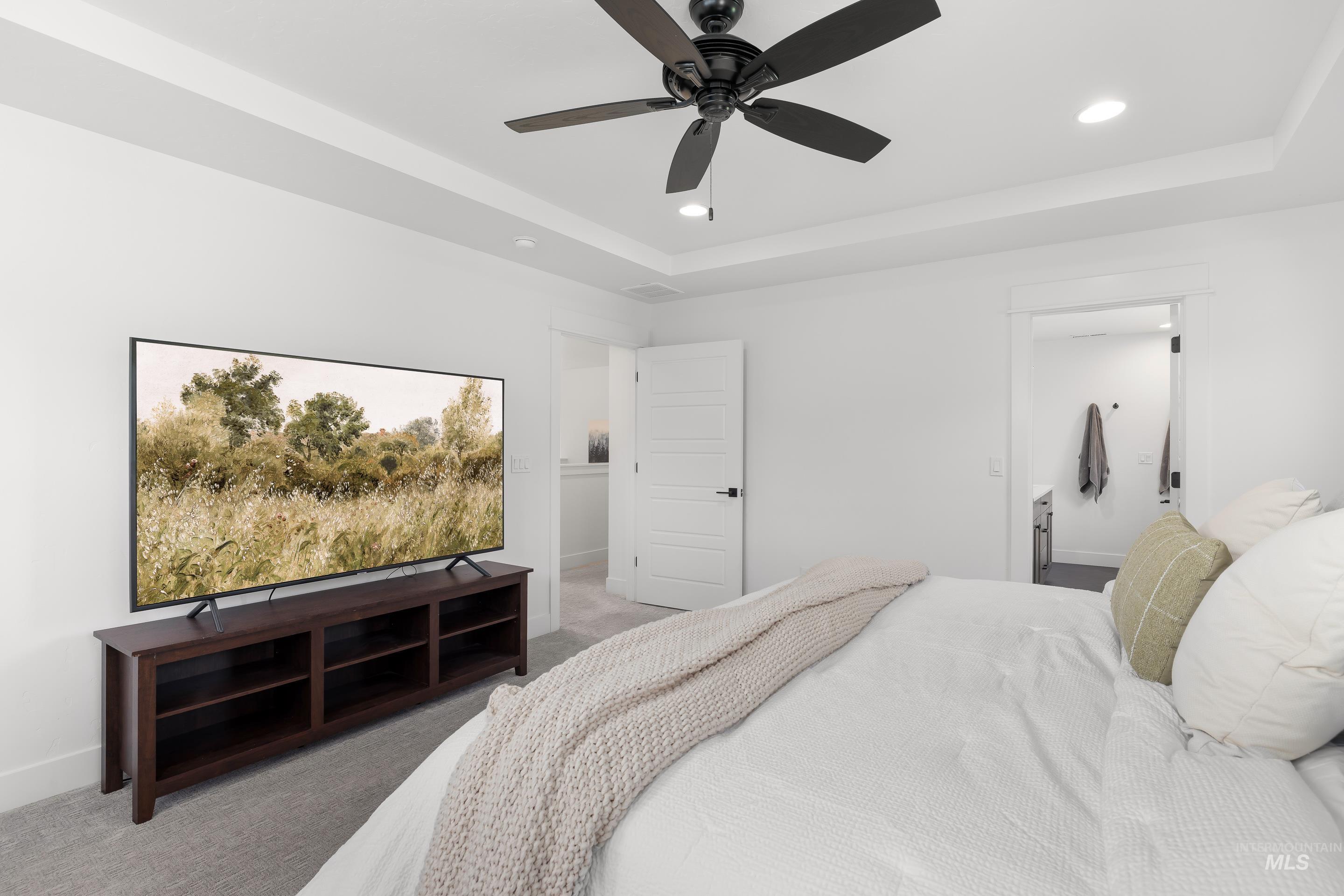 Bedroom featuring a raised ceiling, carpet floors, recessed lighting, and a ceiling fan