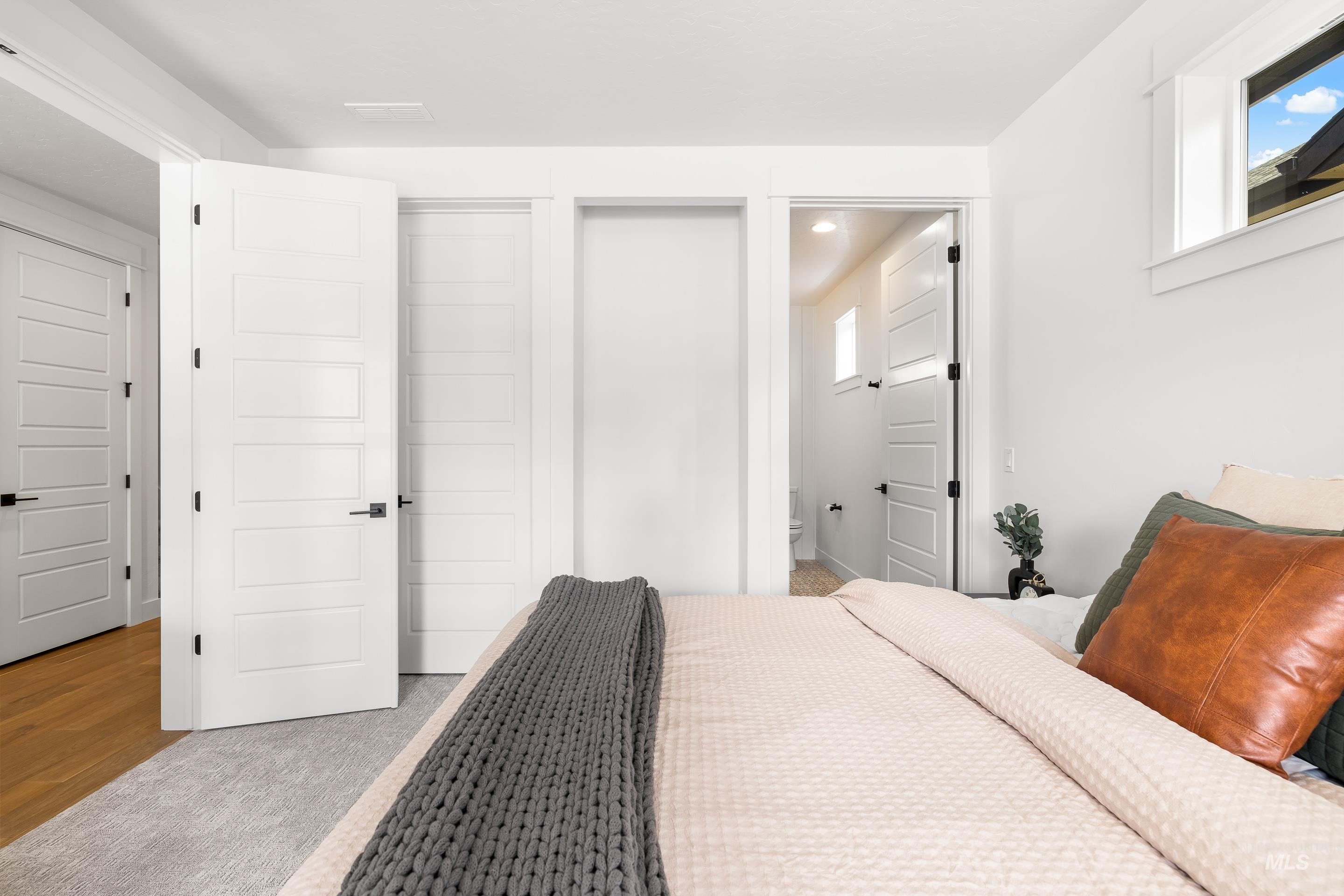 Bedroom featuring connected bathroom, wood finished floors, and multiple windows