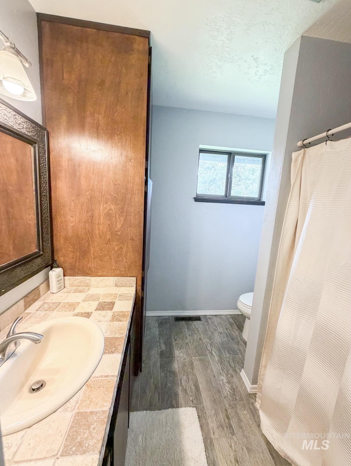 Bathroom vanity with an integrated sink, tiled countertop, and wood-finish cabinetry
