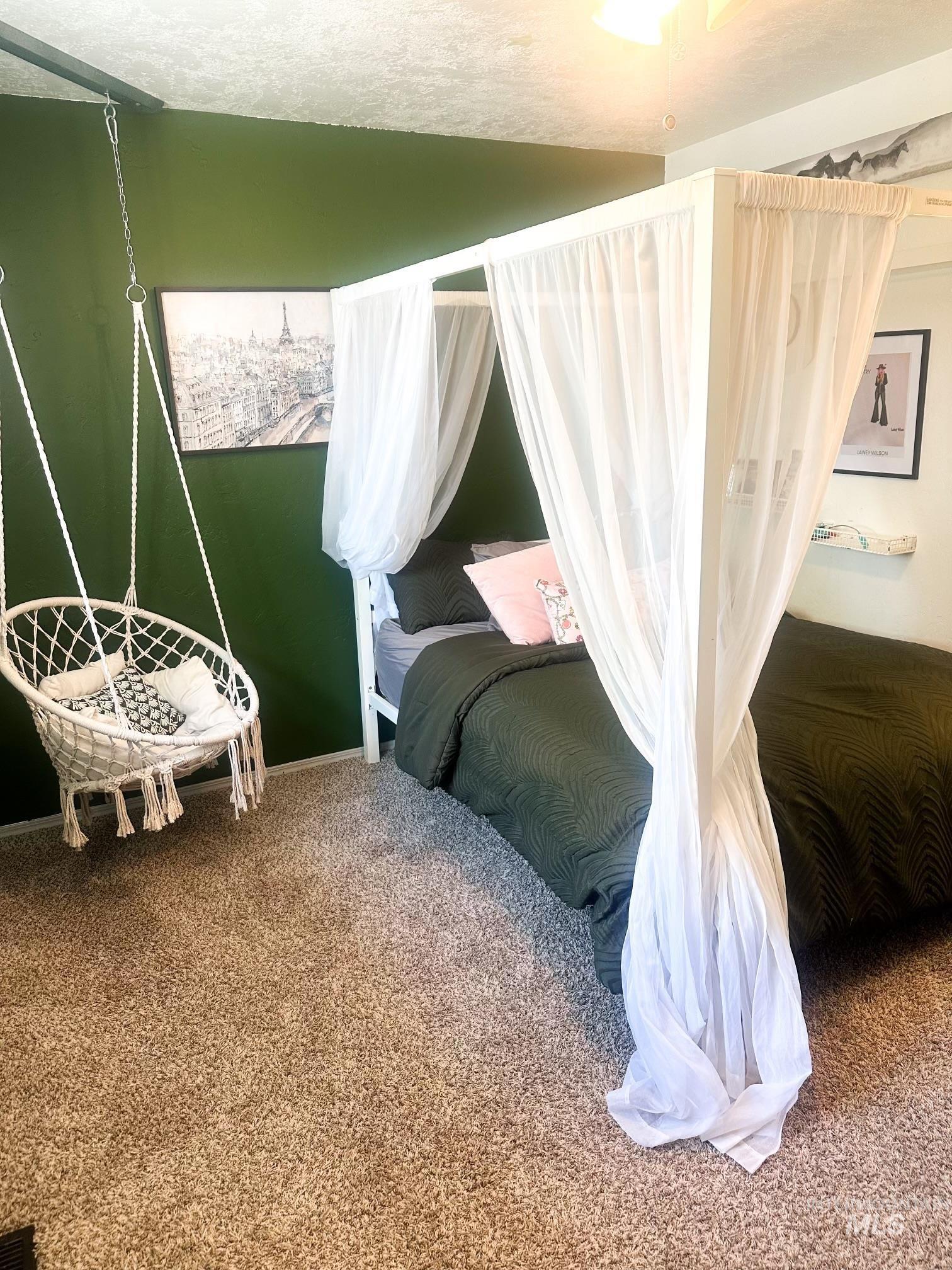 Wall-to-wall carpeting and a dark green accent wall define this bedroom space