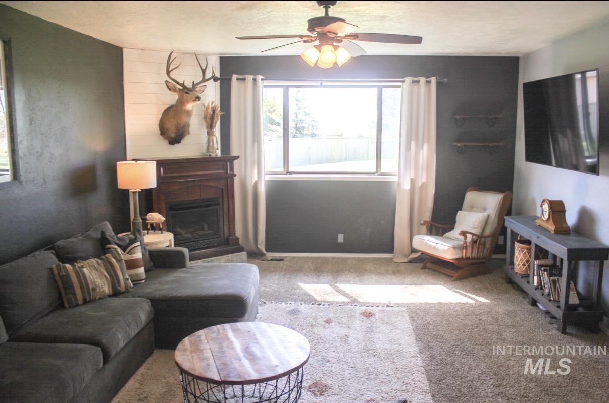 Living area featuring a corner fireplace with a dark wood mantel and a white shiplap accent wall