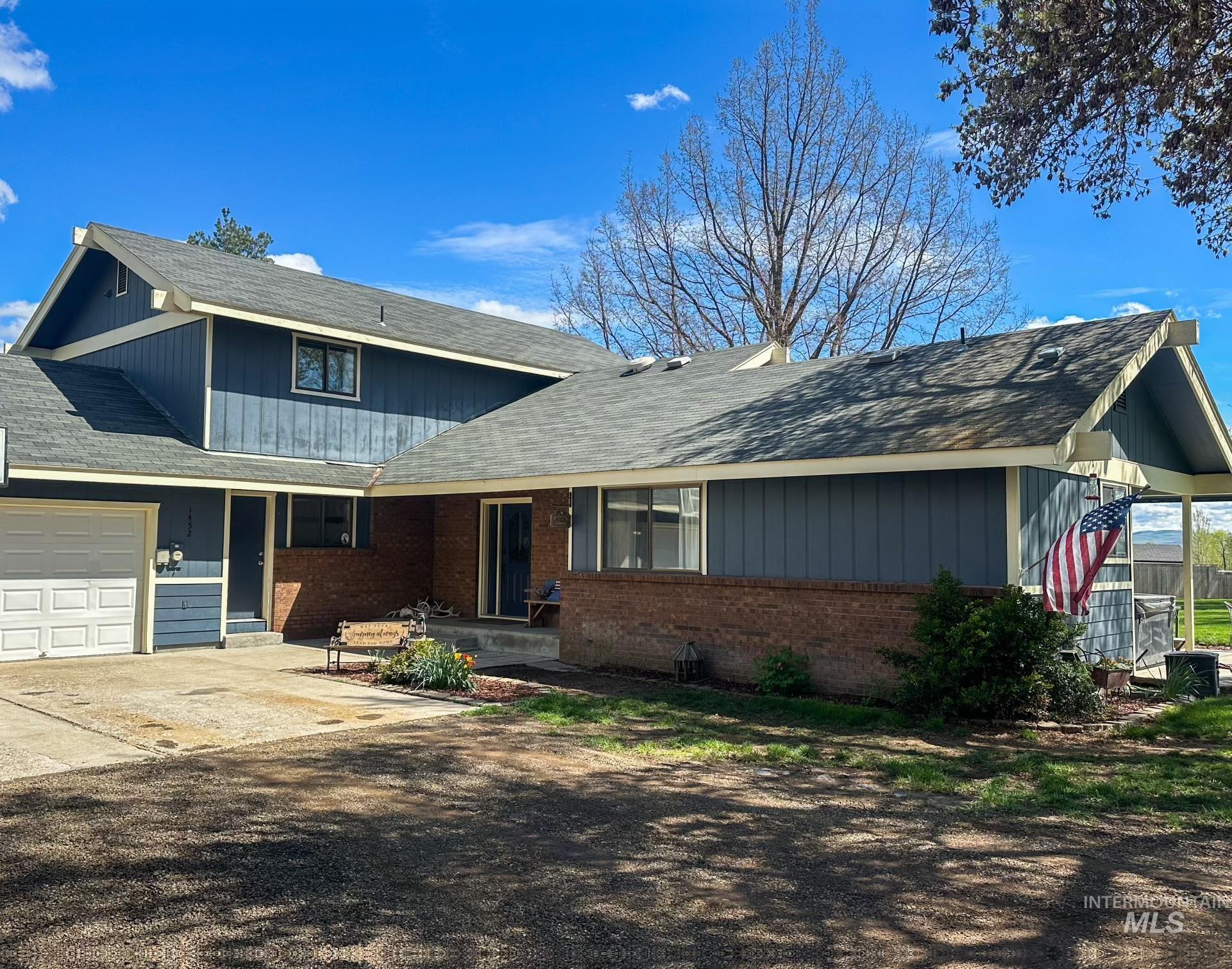 View of front facade with a garage, roof with shingles, brick siding, and driveway