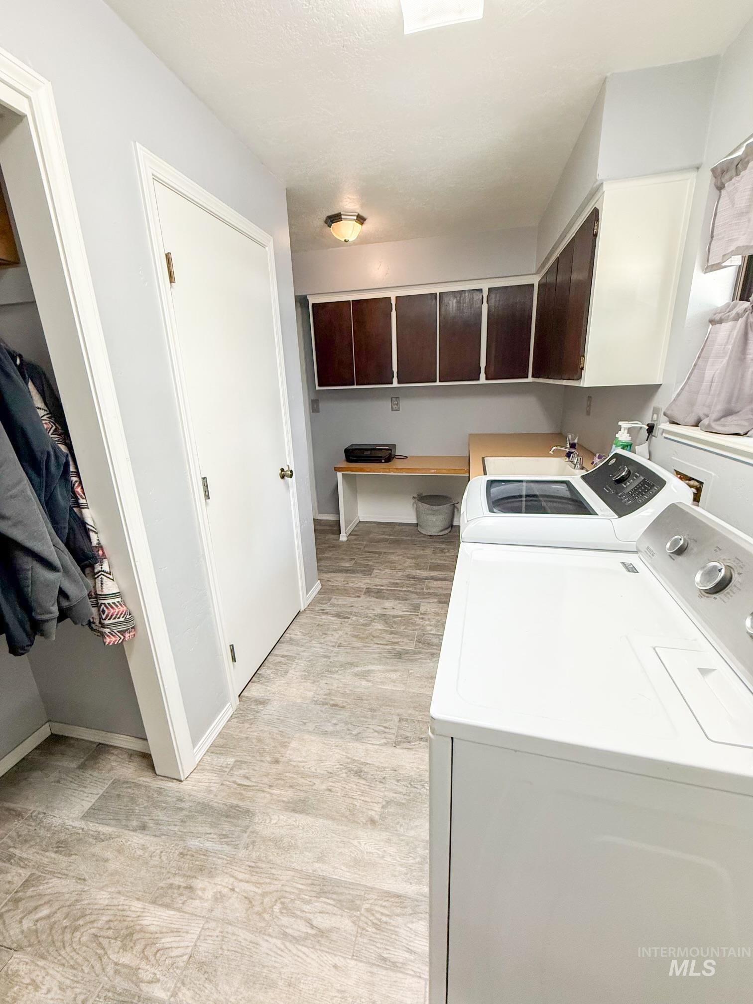 Laundry room featuring wood-finish flooring, built-in cabinetry, an integrated sink, and an expansive countertop workspace