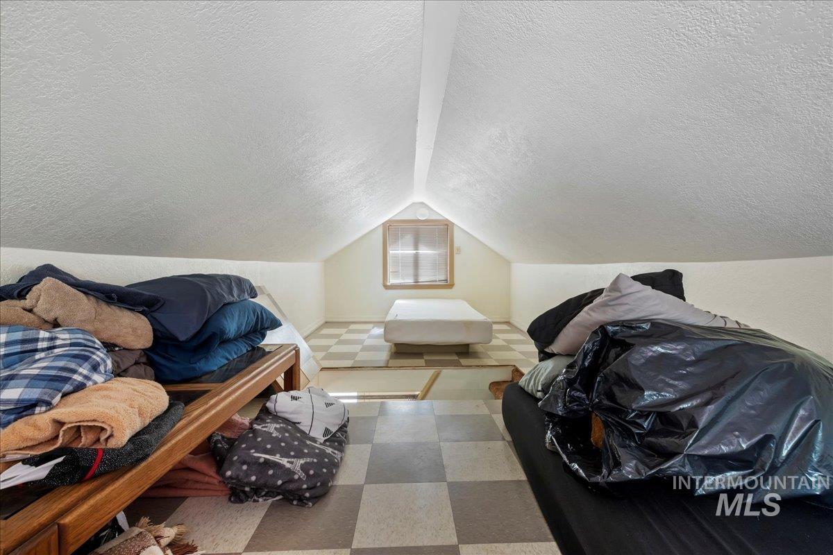 Additional living space with a textured ceiling, lofted ceiling, and tile patterned floors