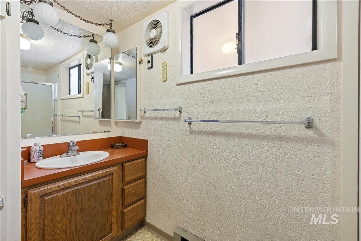 Full bathroom featuring vanity, a stall shower, a textured ceiling, and a textured wall