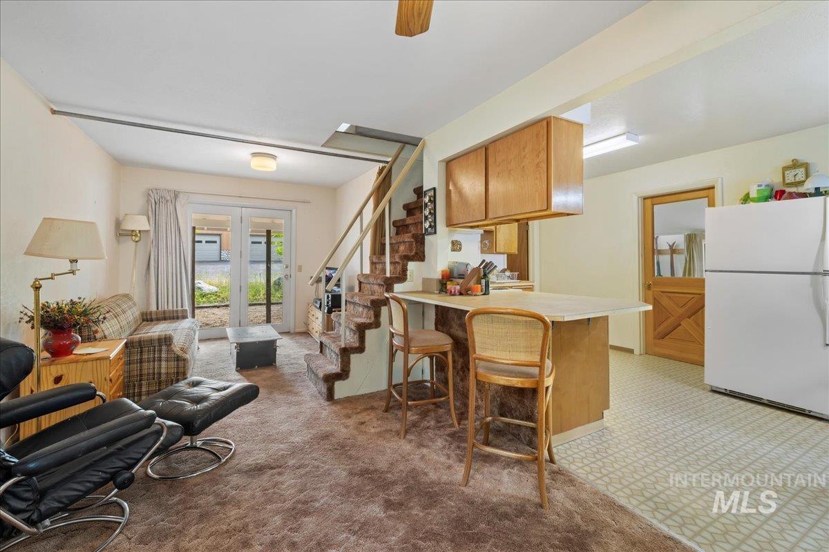 Living area featuring light carpet, stairway, and ceiling fan