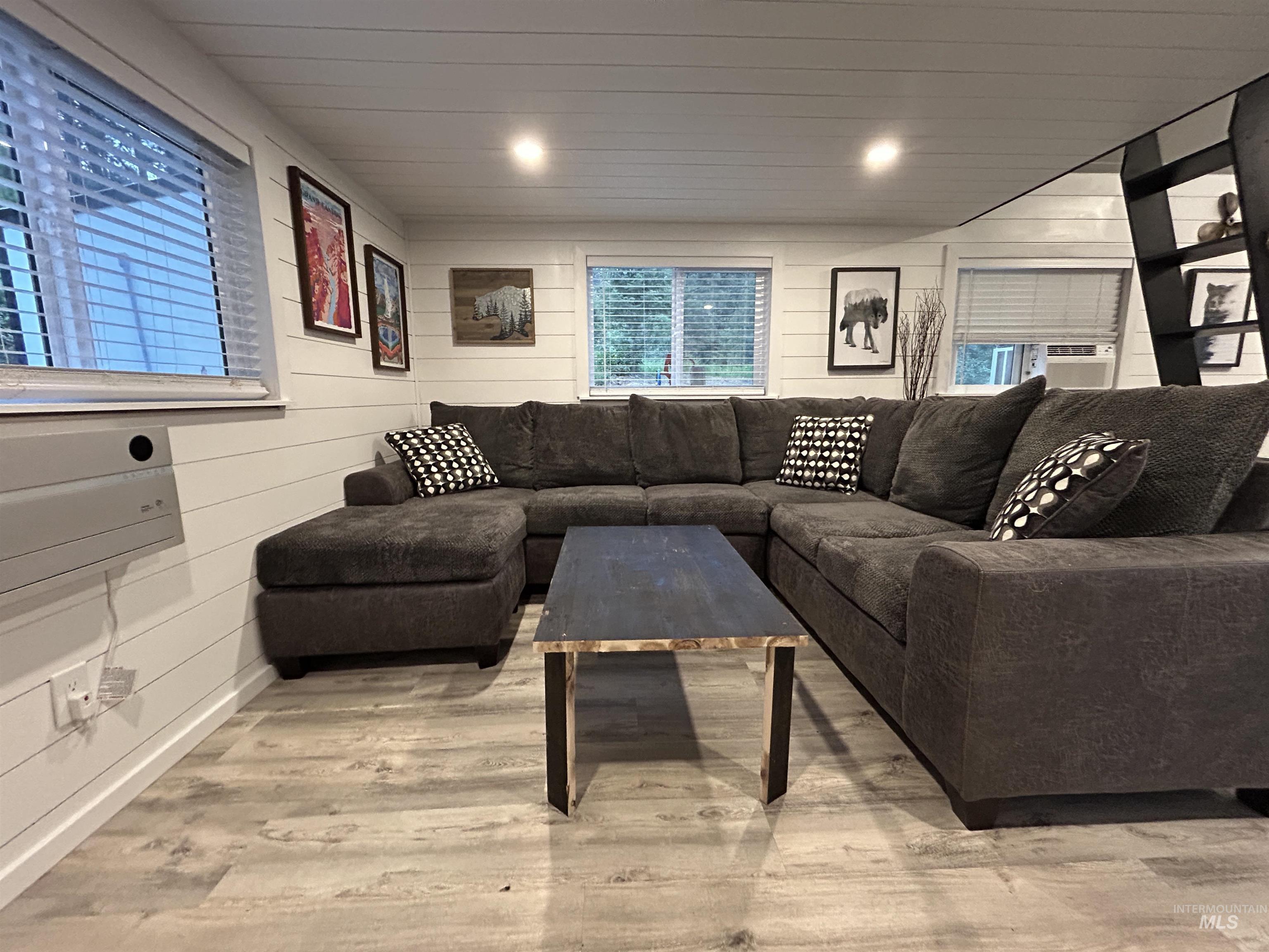 Living room with light wood finished floors and wooden walls