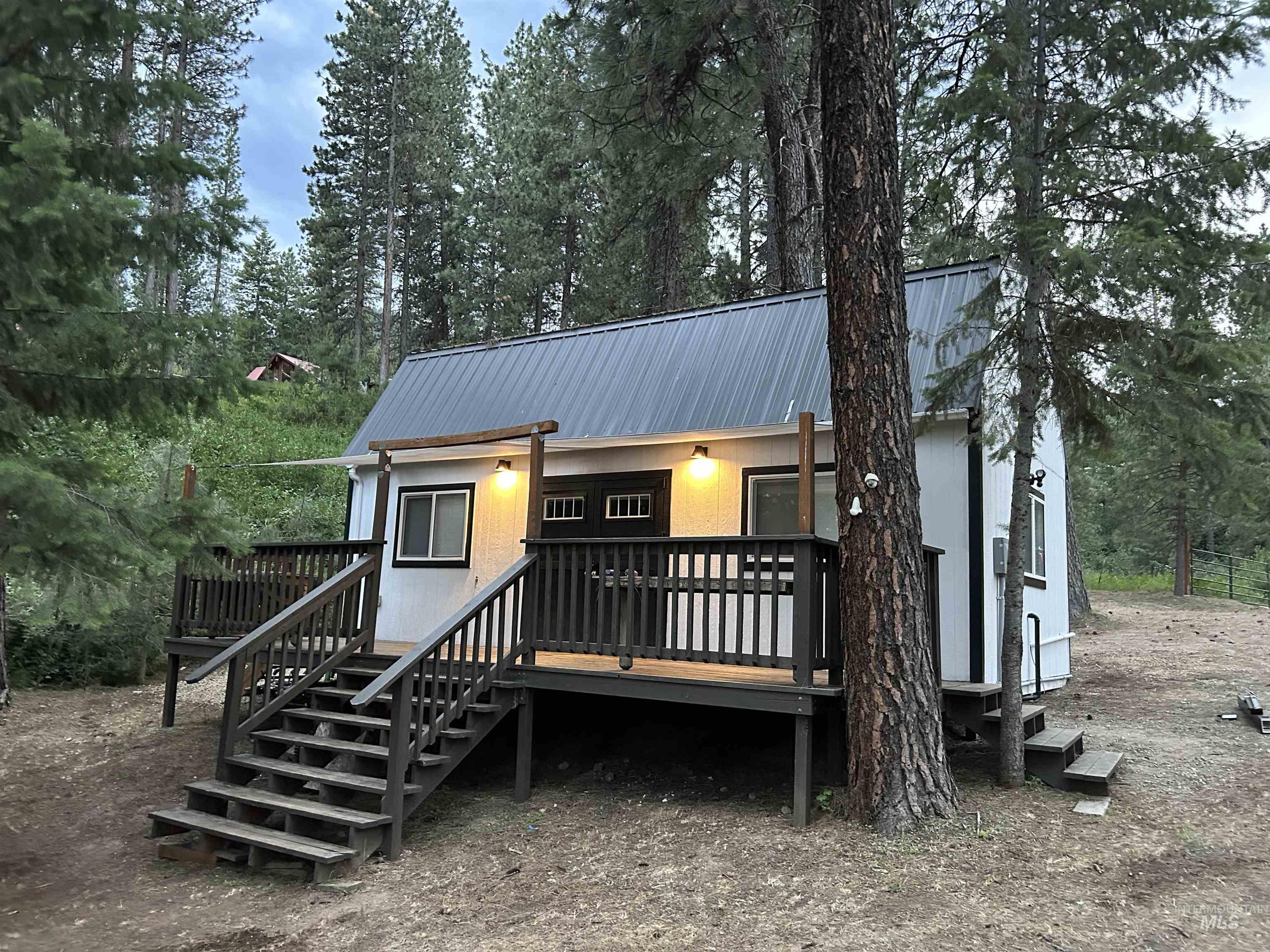 View of front of house featuring a wooden deck, a metal roof, and stairs
