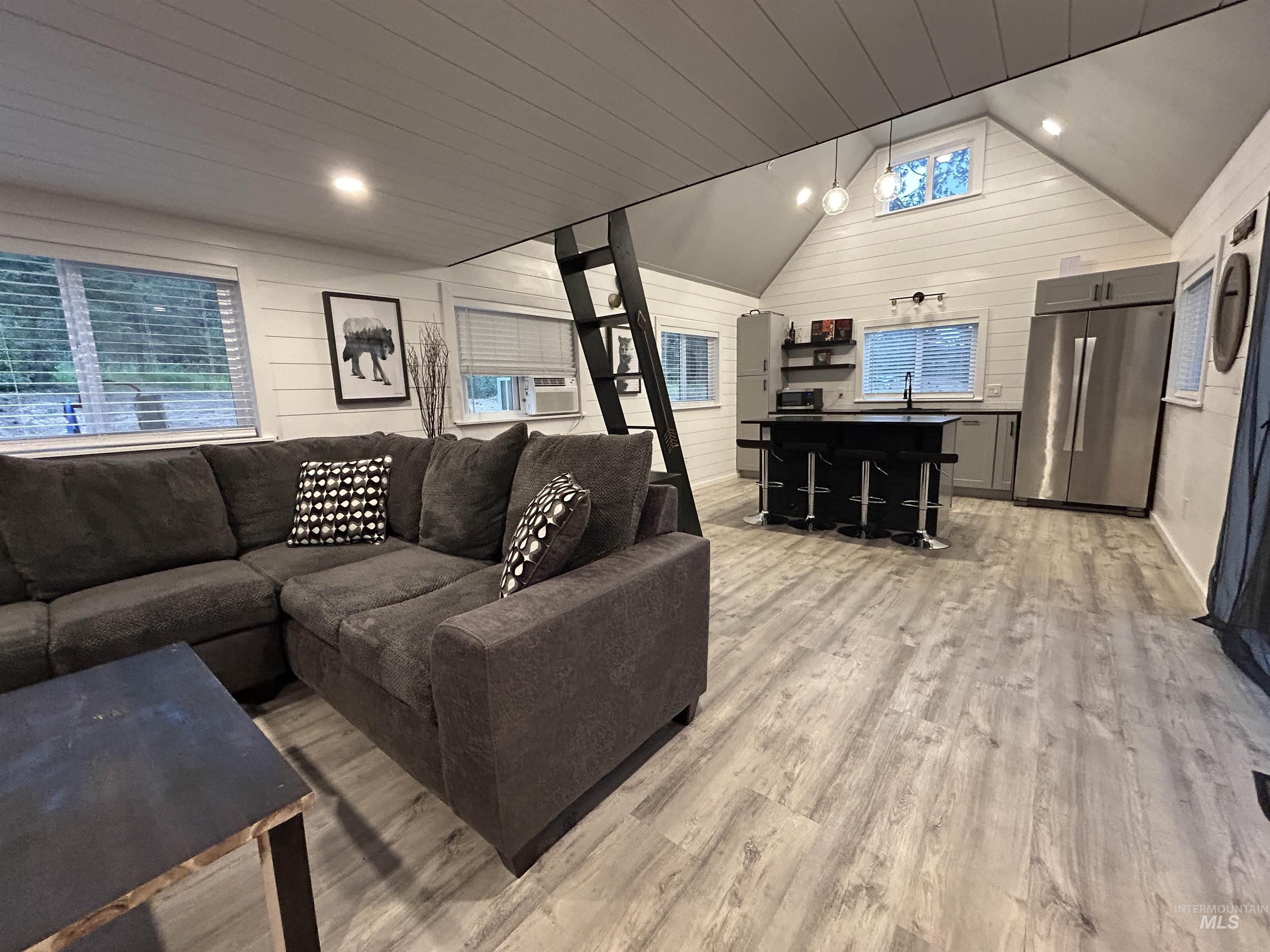 Living area featuring light wood-style flooring, lofted ceiling, and wooden walls