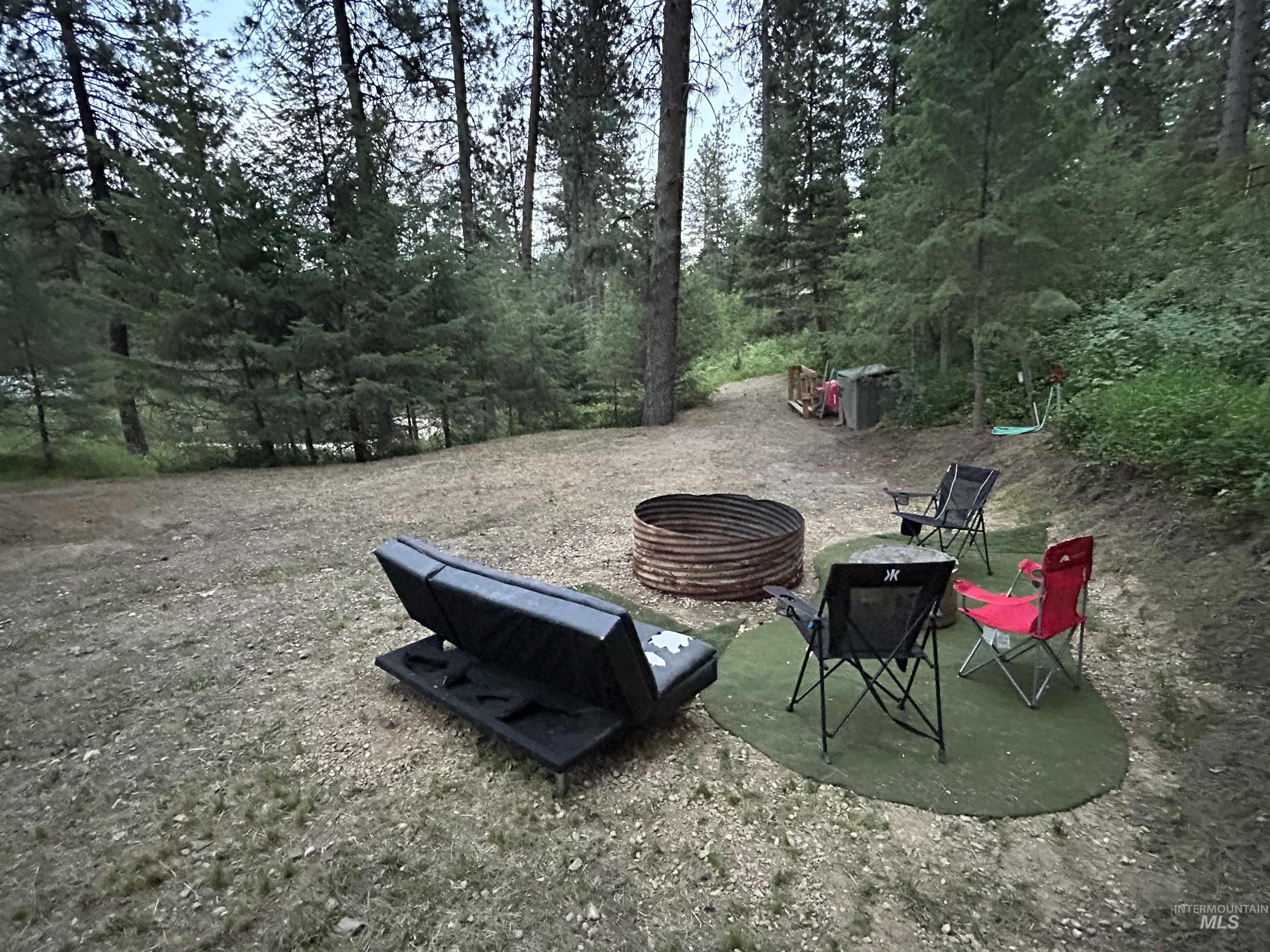View of yard featuring a fire pit and a view of trees