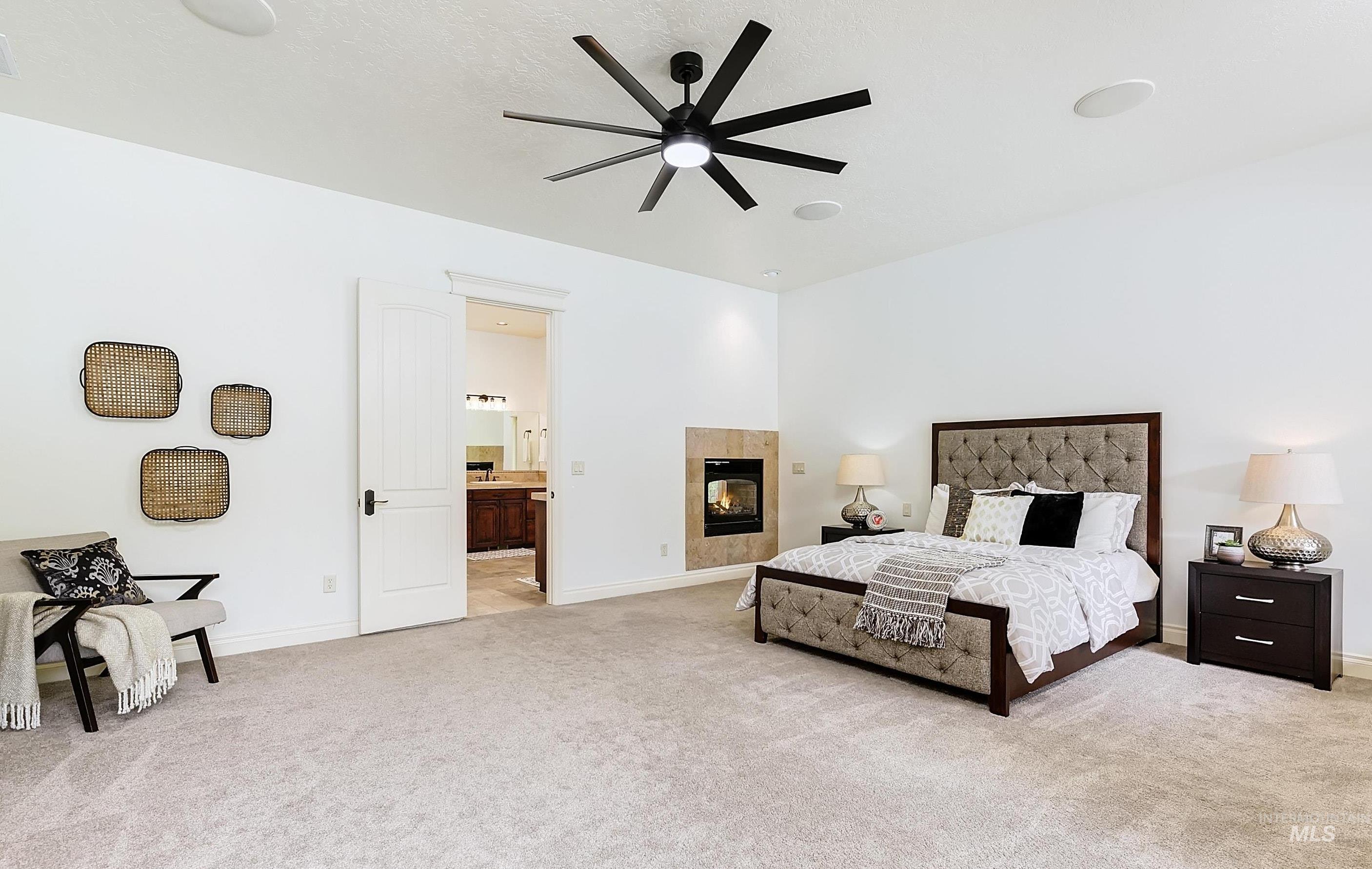 Bedroom featuring a ceiling fan, light colored carpet, a fireplace, and connected bathroom