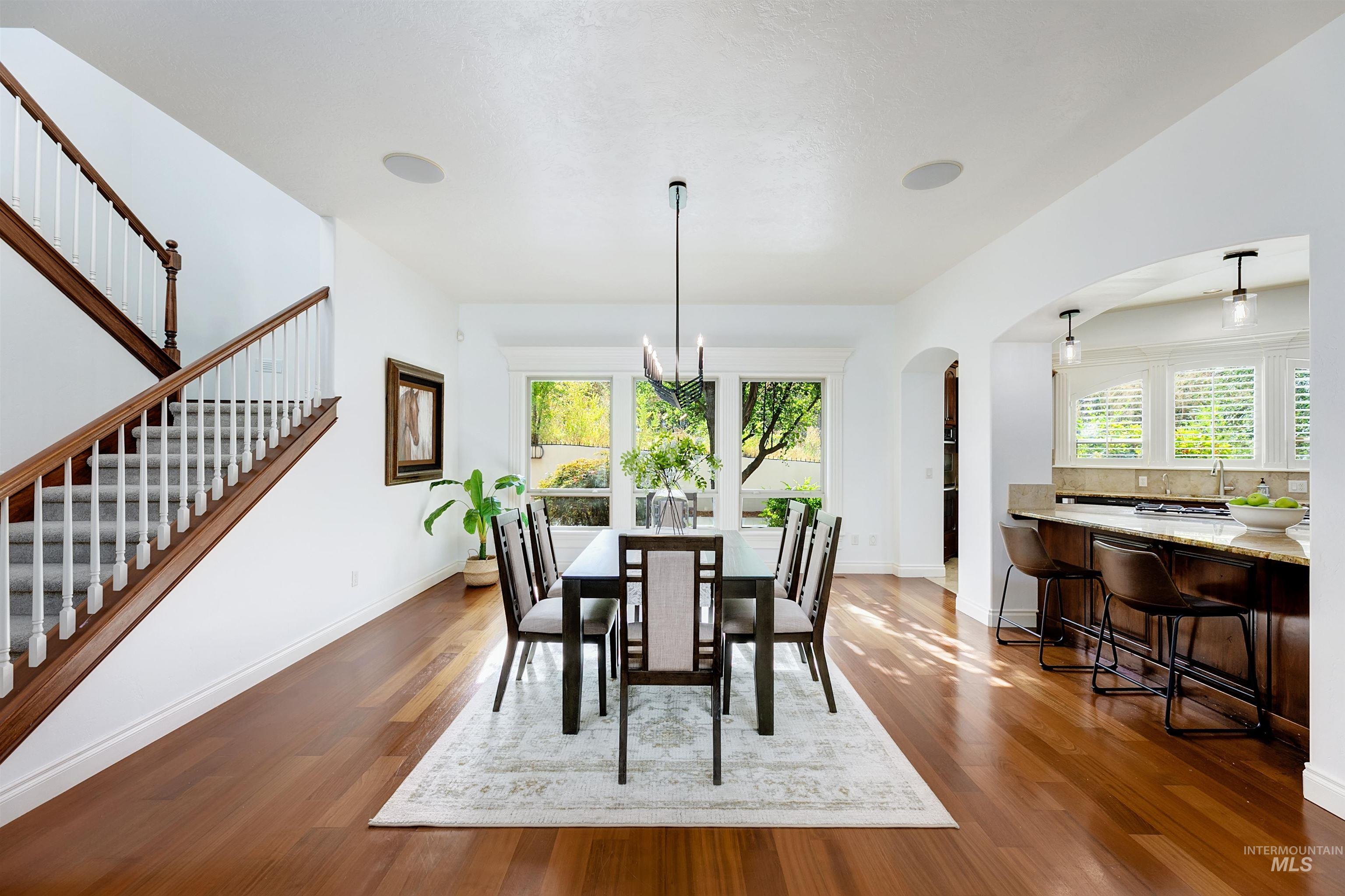 Dining area with plenty of natural light, arched walkways, dark wood finished floors, and a chandelier