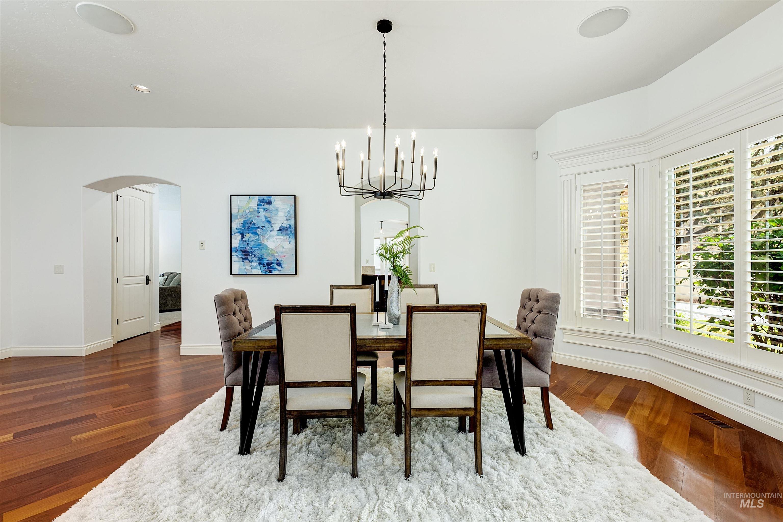 Dining area with arched walkways, hanging lights, and dark wood finished floors