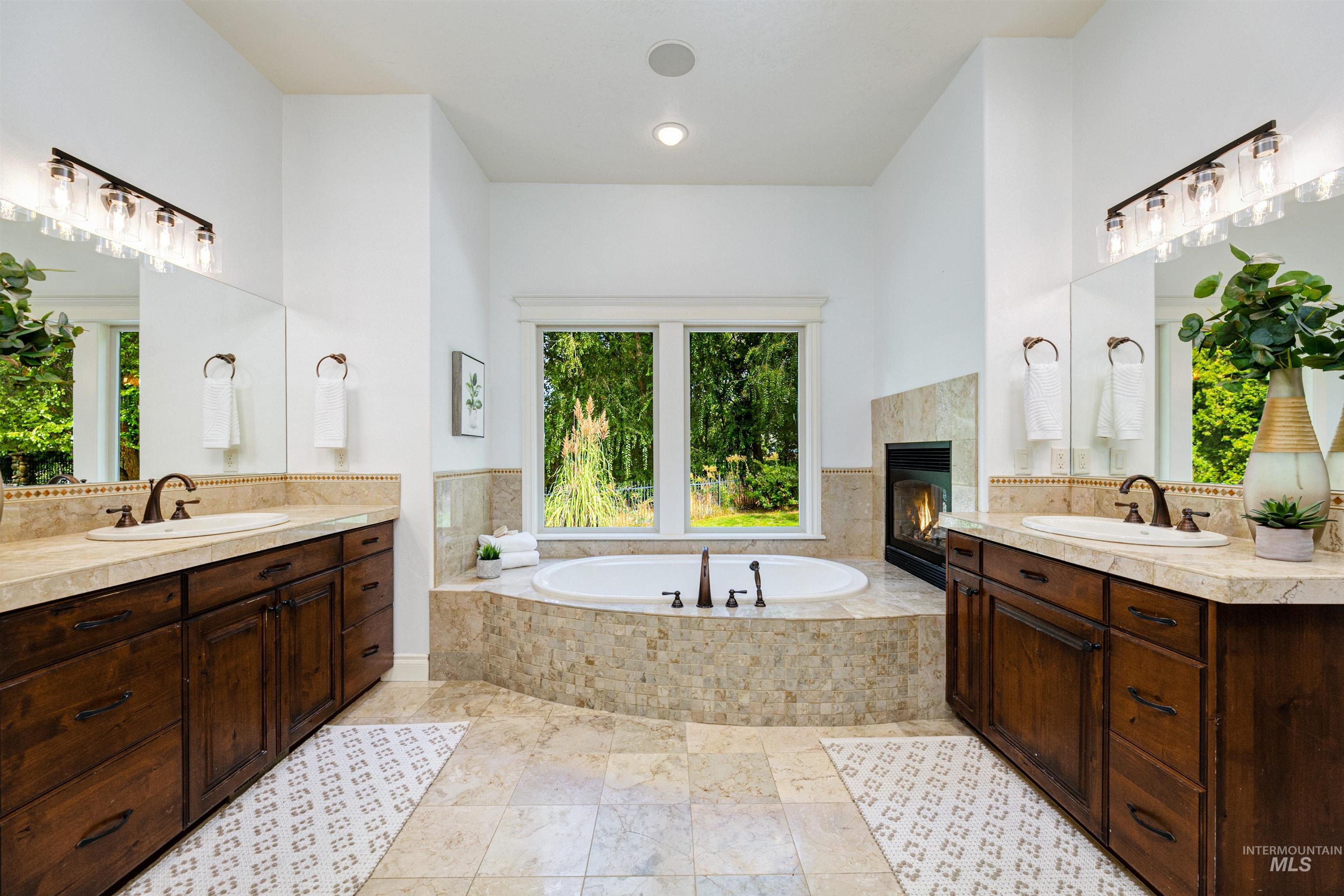 Full bath with two vanities, a garden tub, and a tile fireplace