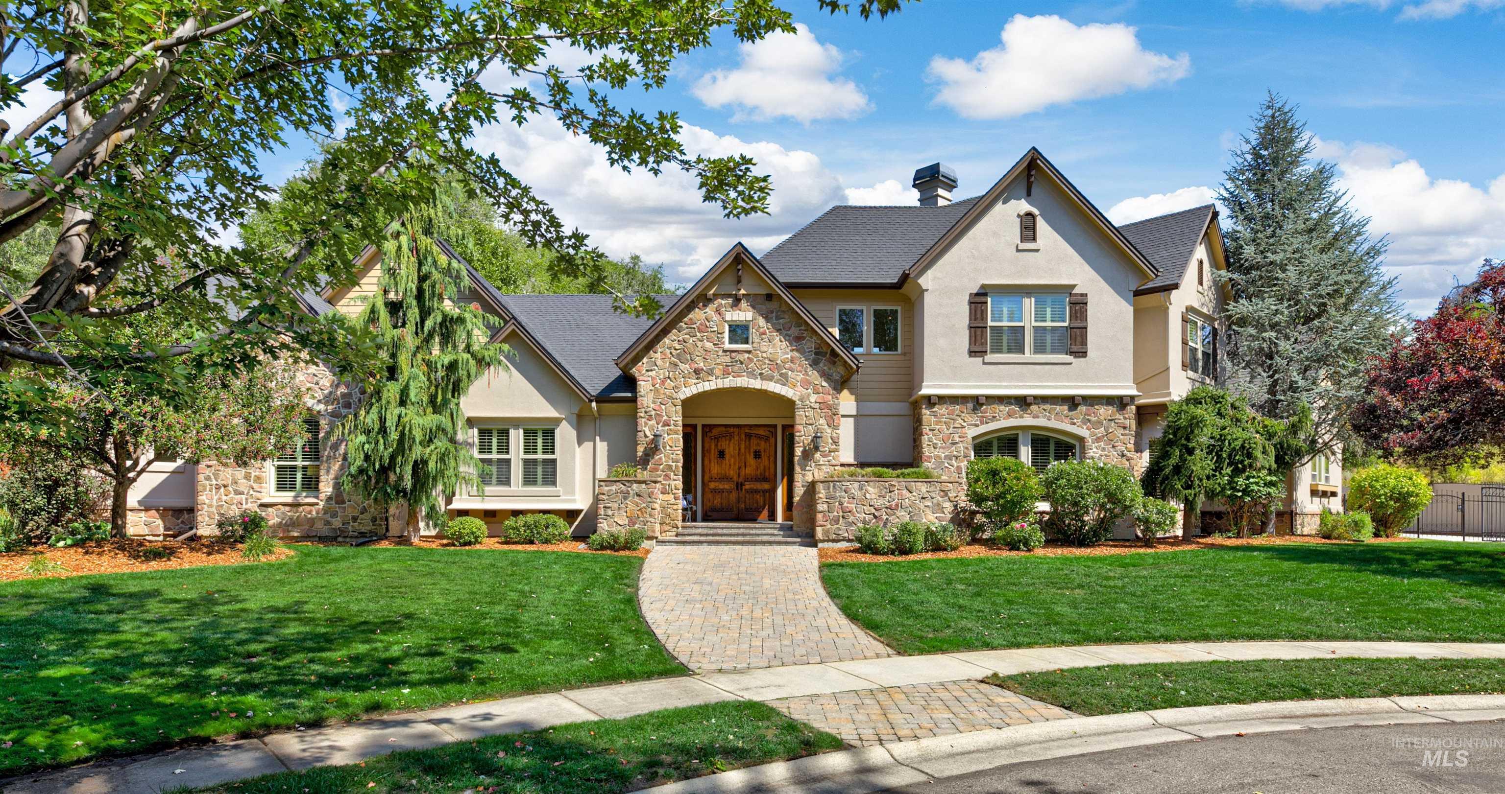 Tudor-style house with stone siding, a front lawn, and stucco siding