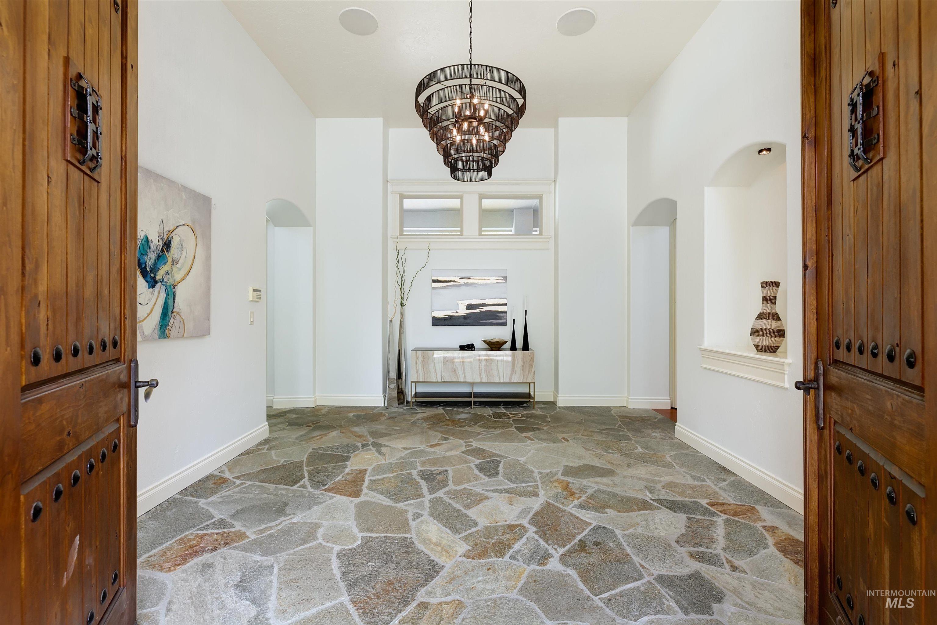 Entryway featuring arched walkways, a chandelier, and stone floors