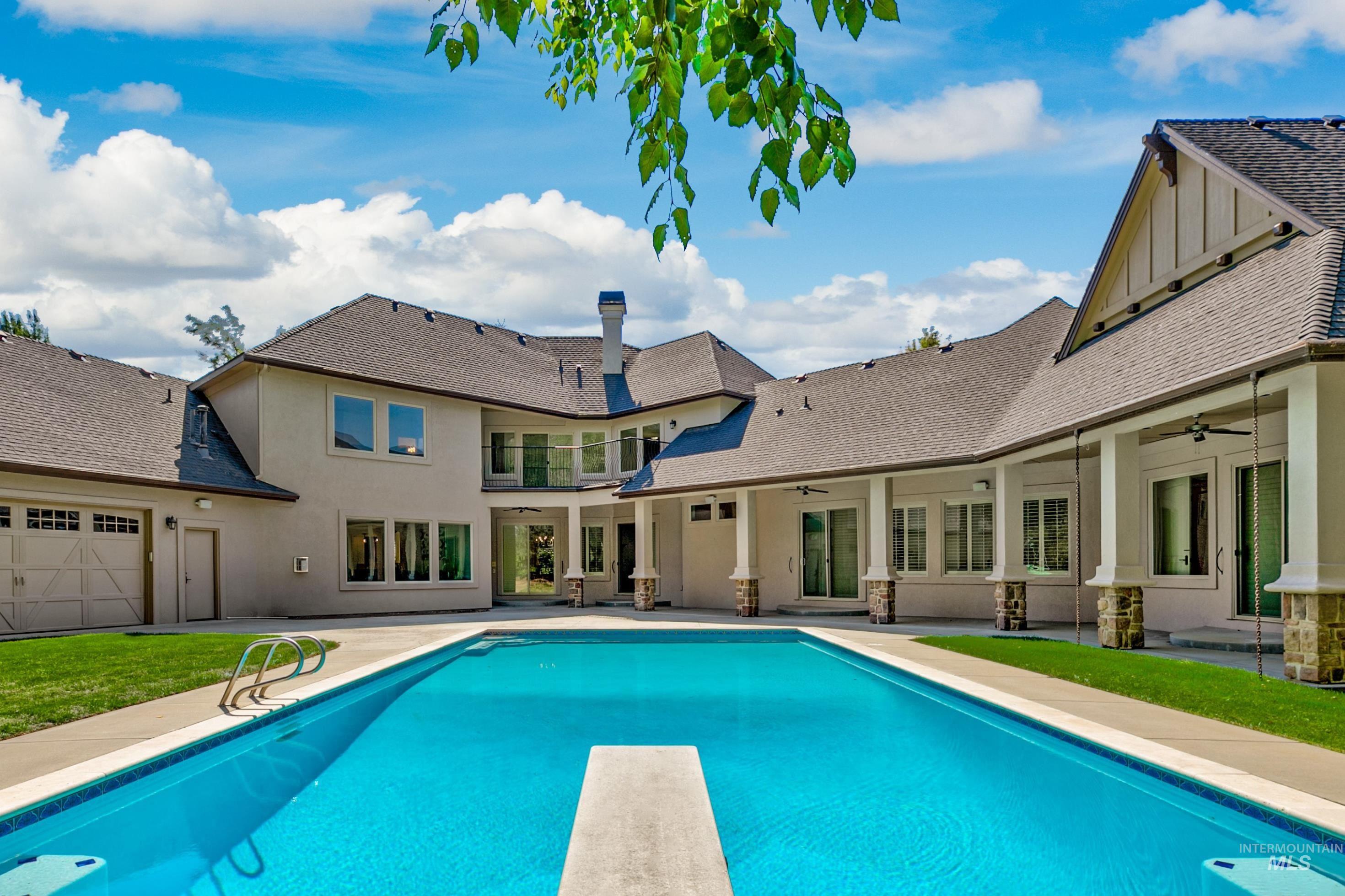 Swimming pool with a diving board, a patio, and a yard