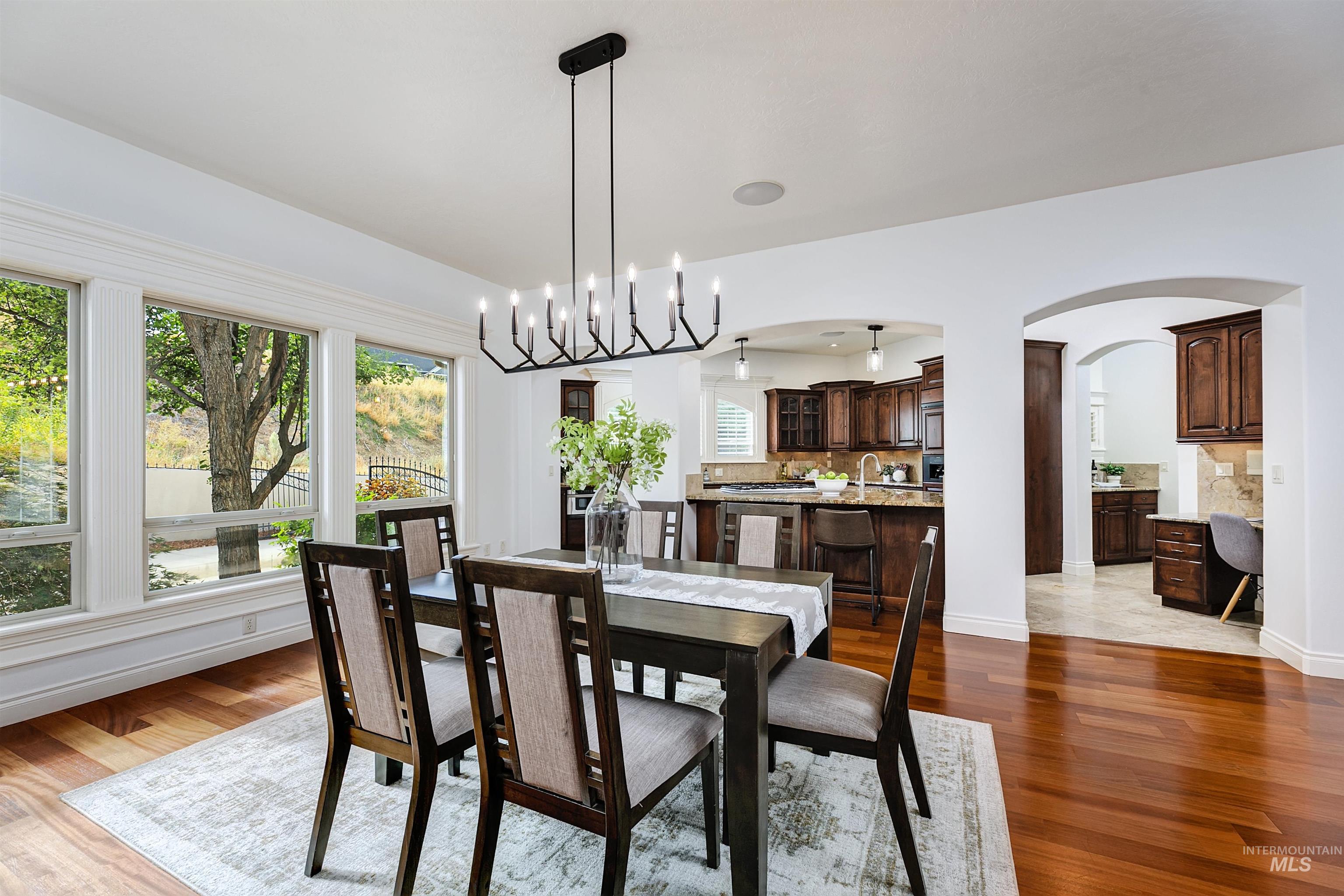 Dining area with arched walkways, dark wood-type flooring, and hanging lights