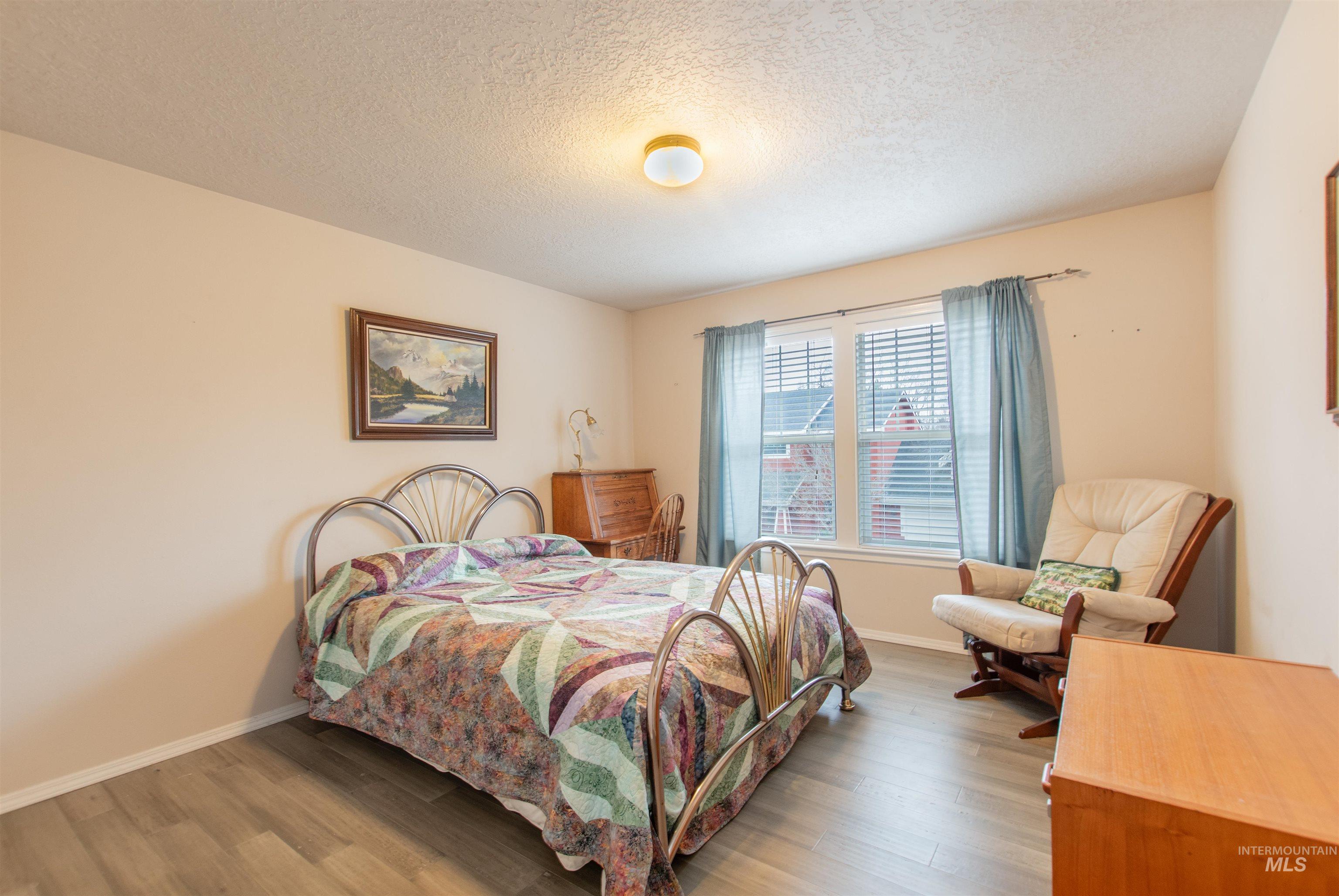 Bedroom with wood finished floors and a textured ceiling