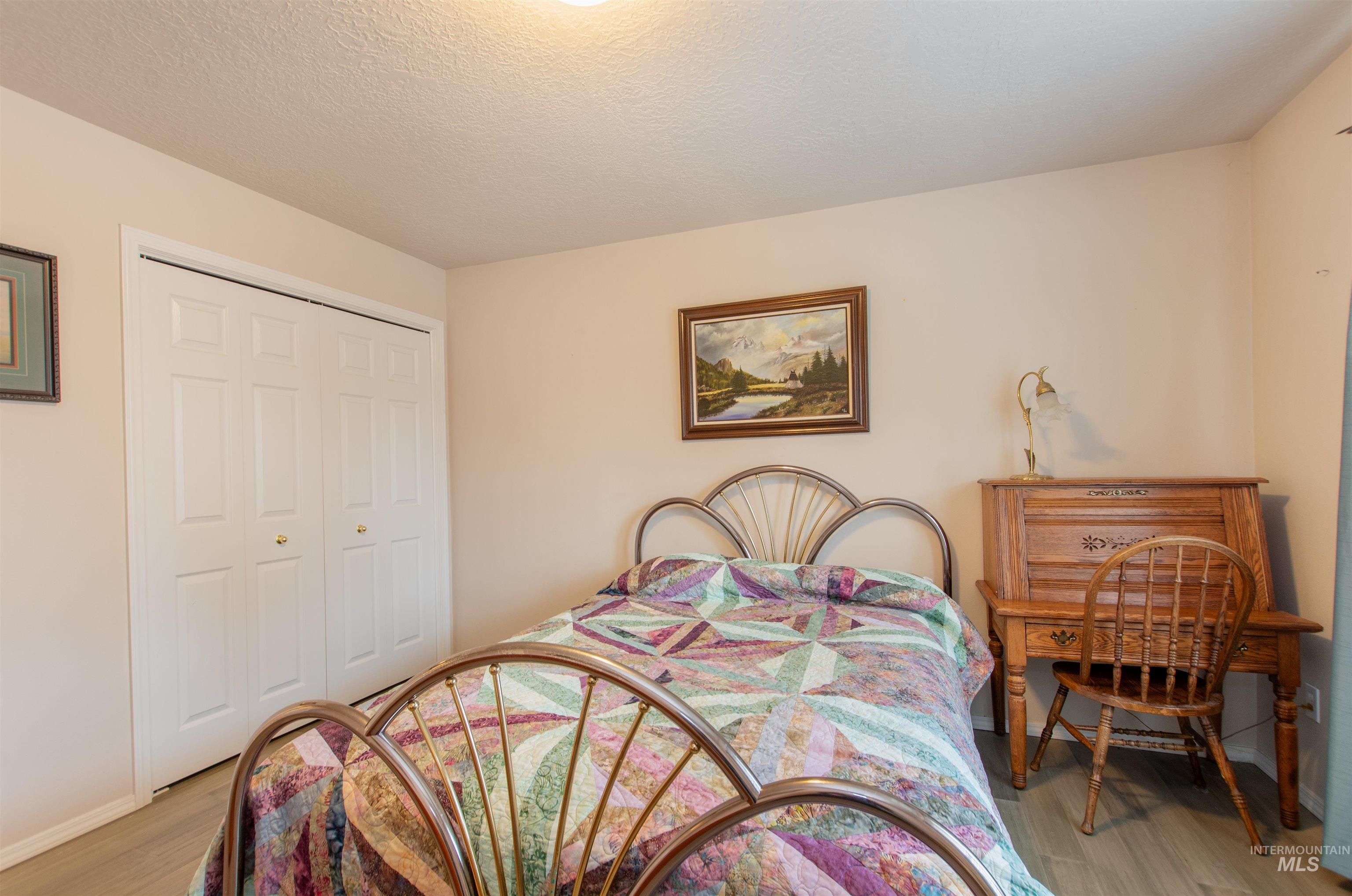 Bedroom with a closet, light wood-style floors, and a textured ceiling