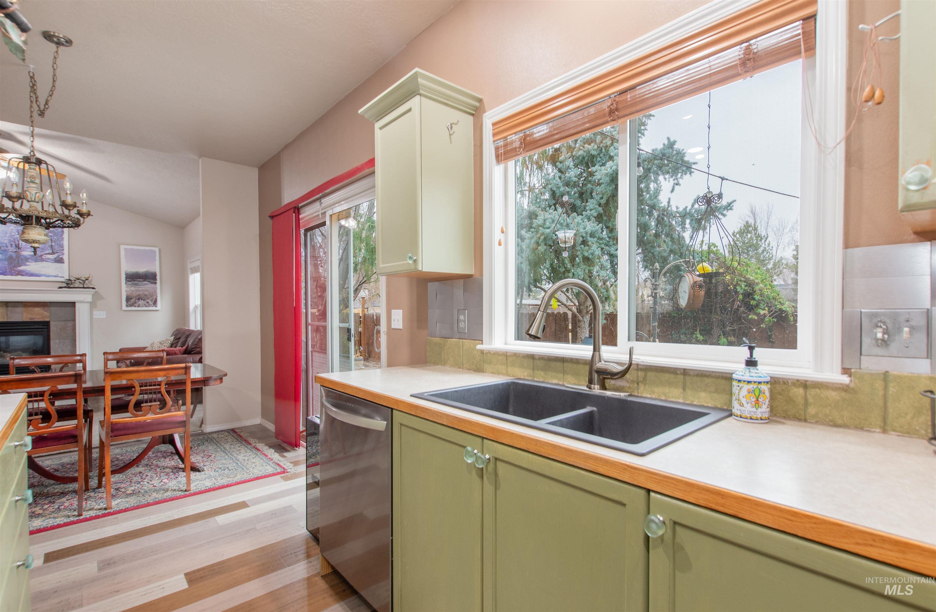 Kitchen with light countertops, dishwasher, light wood finished floors, a chandelier, and vaulted ceiling