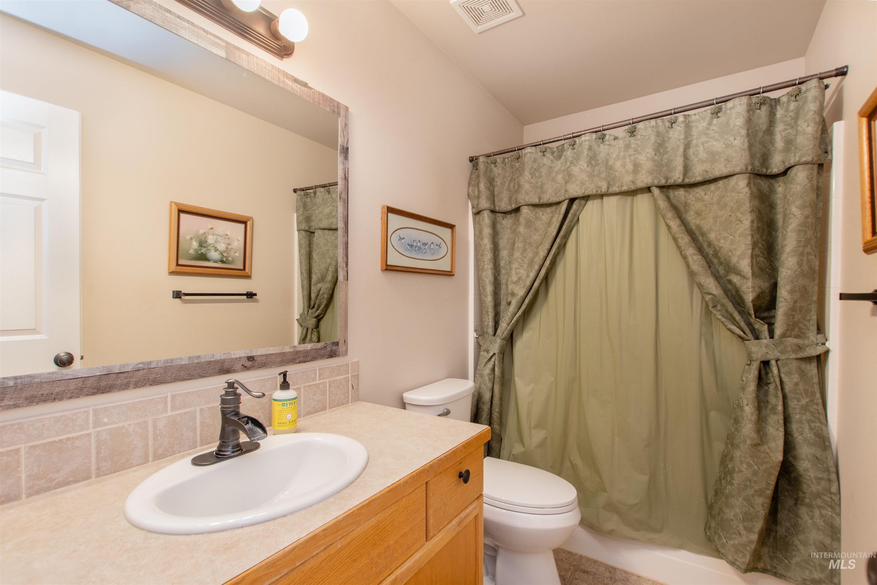 Bathroom with a shower with shower curtain, vanity, and backsplash