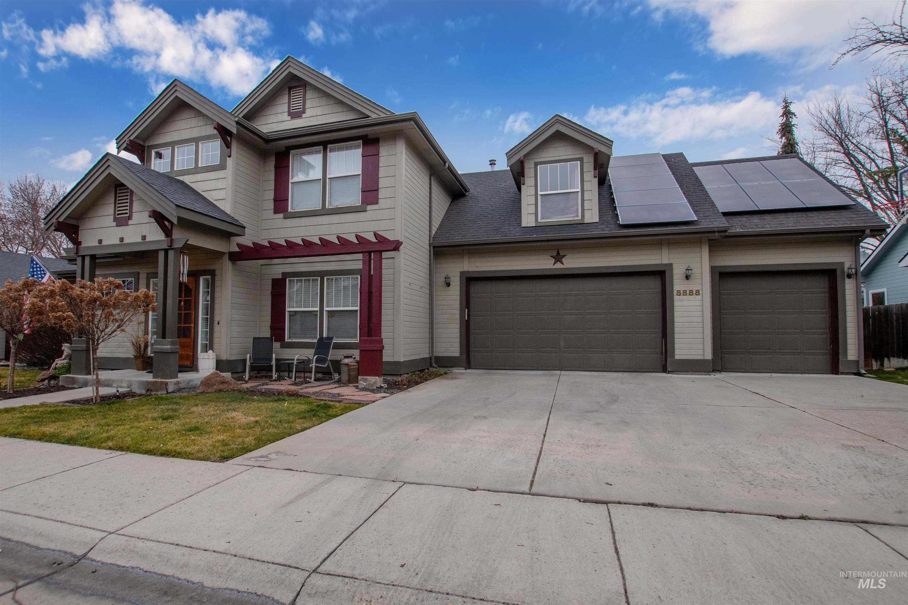 View of front of house featuring roof mounted solar panels, driveway, a garage, a shingled roof, and a front yard