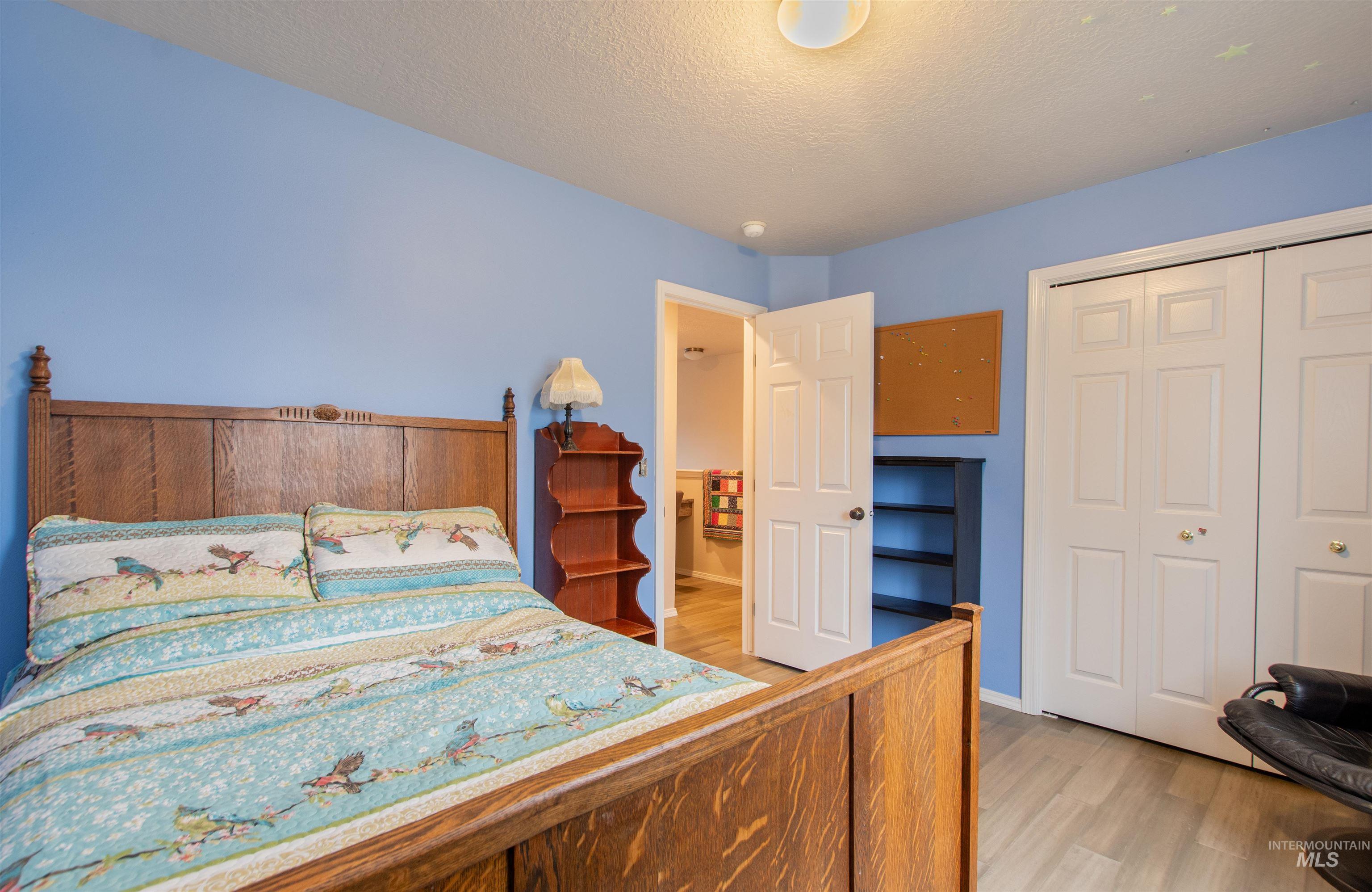 Bedroom featuring a closet, light wood-type flooring, and a textured ceiling