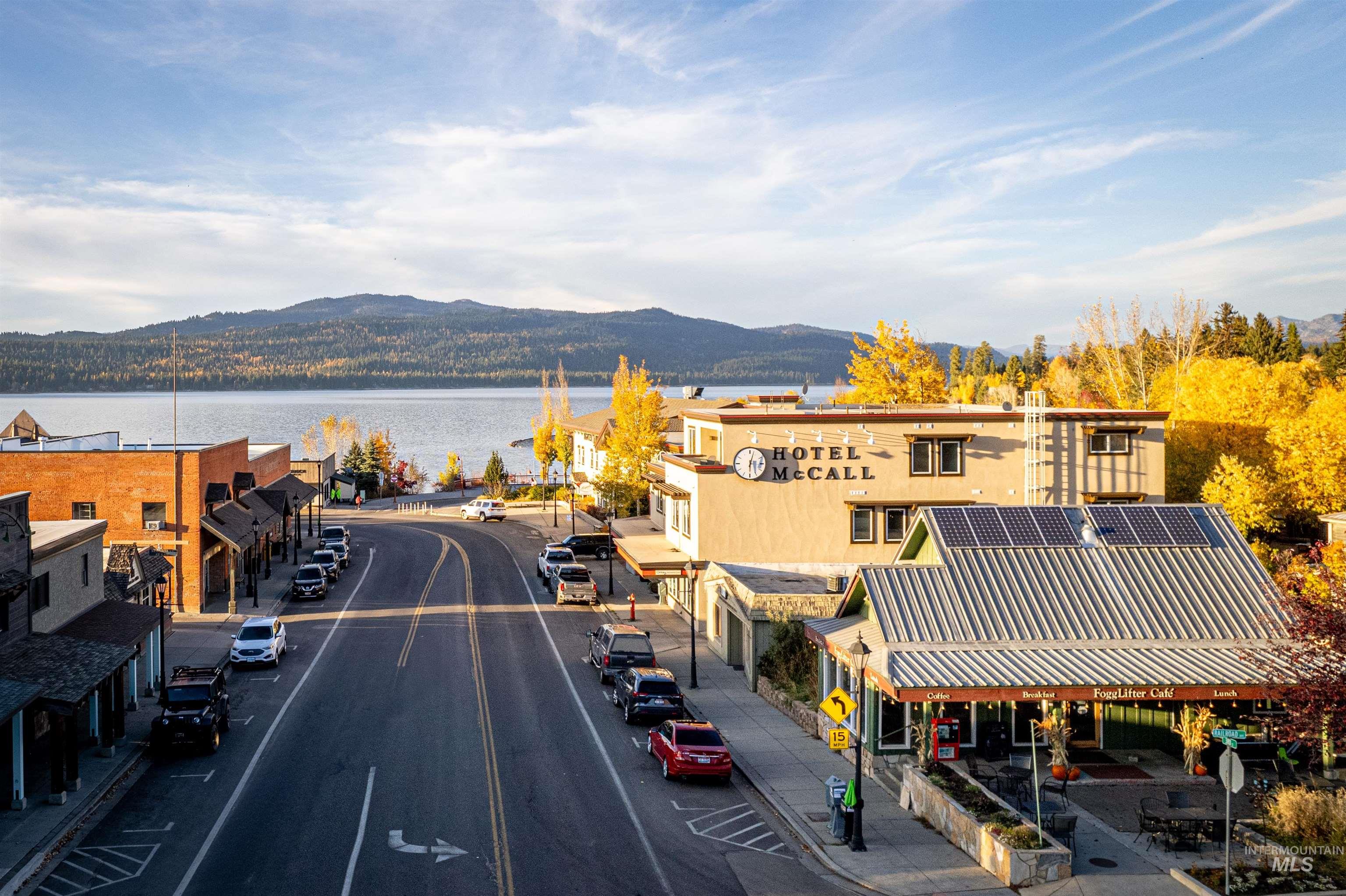 View of asphalt road with sidewalks, curbs, street lighting, and a water and mountain view