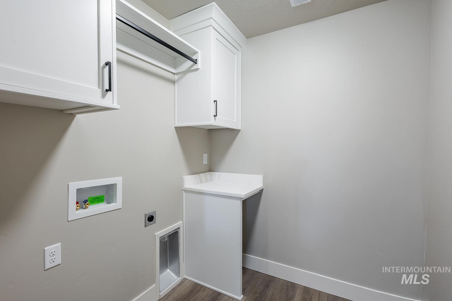 Utility room featuring white cabinetry with black hardware, a built-in hanging rod, dedicated appliance hookups, a counter space, and wood-finish flooring
