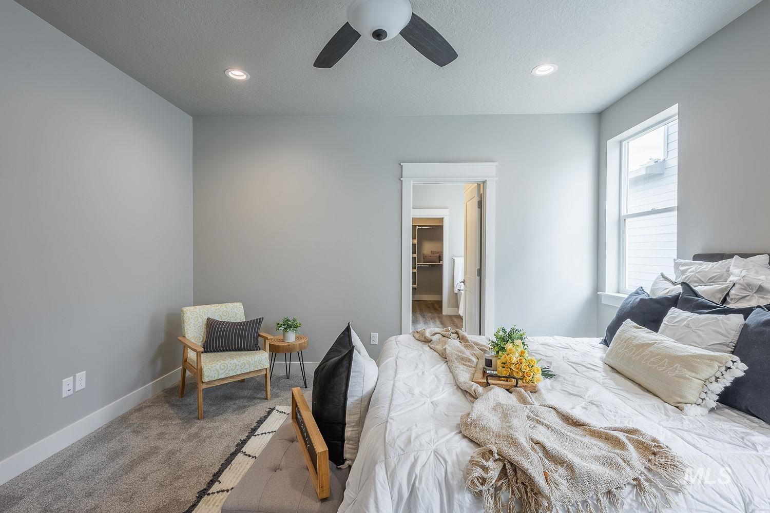 Carpeted bedroom featuring a large window with white trim, recessed lighting, and a ceiling fan