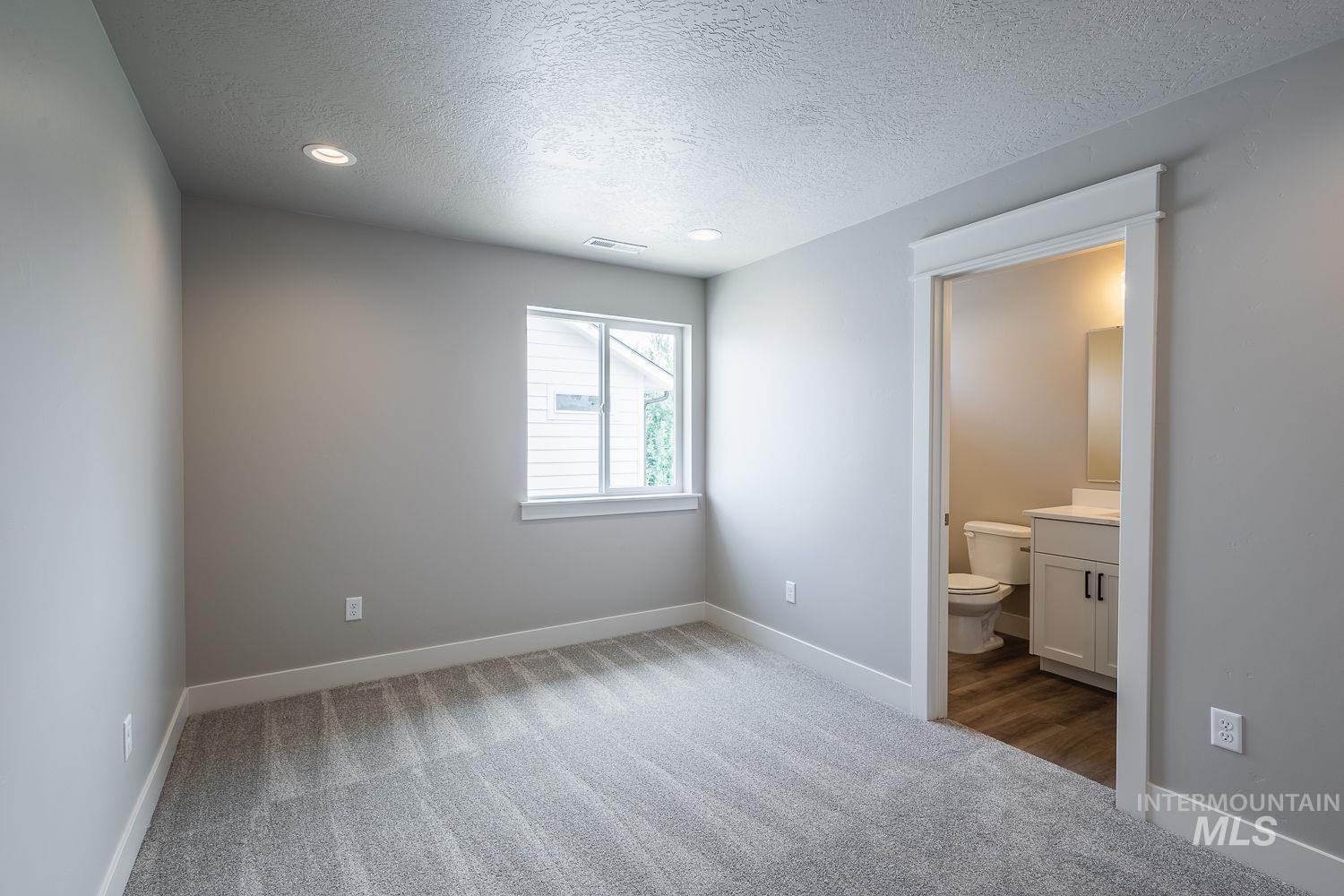 Spacious room featuring neutral grey walls and new grey carpet