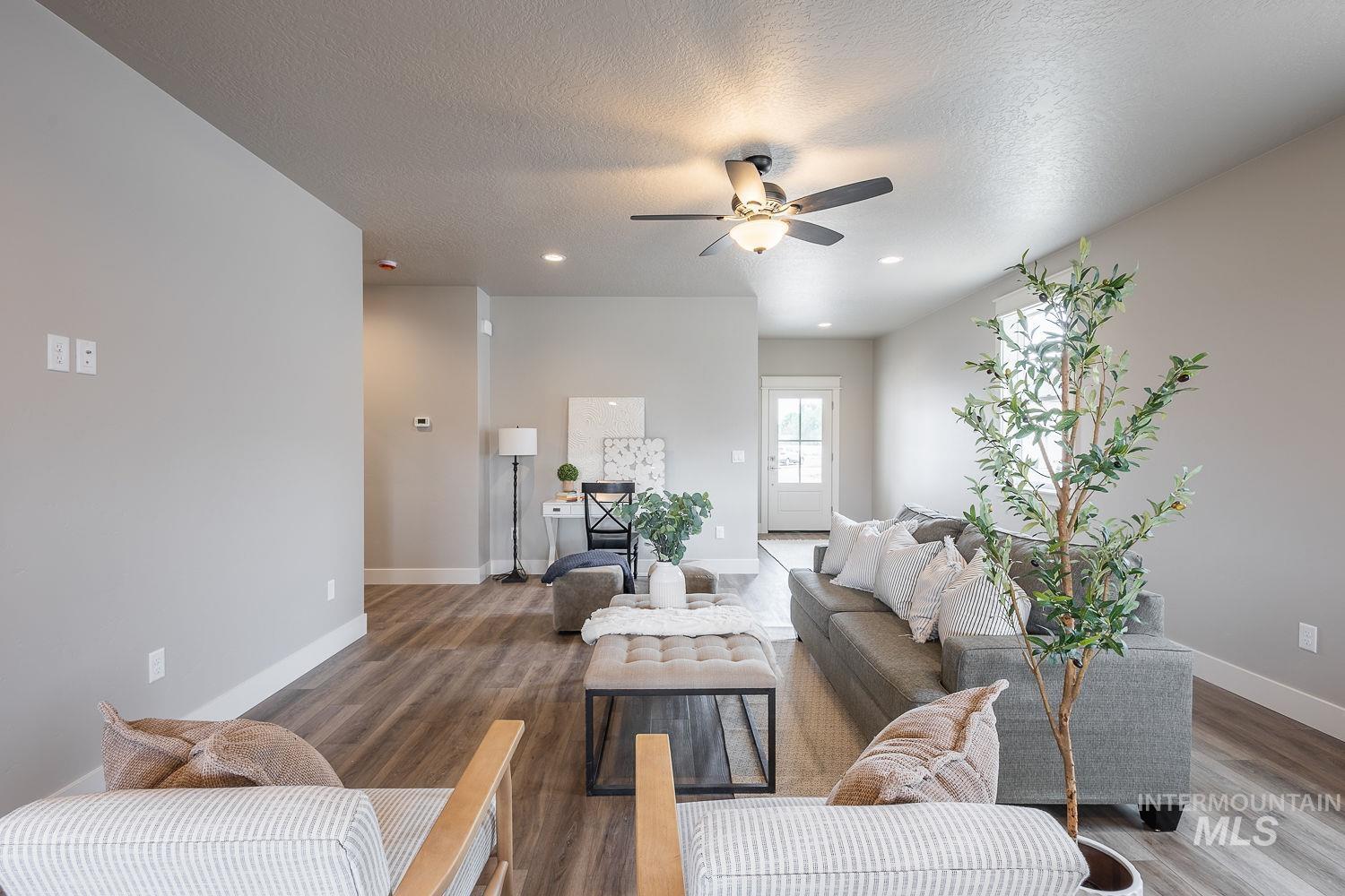 Open-concept living space featuring wood-finish flooring, recessed lighting, and a ceiling fan