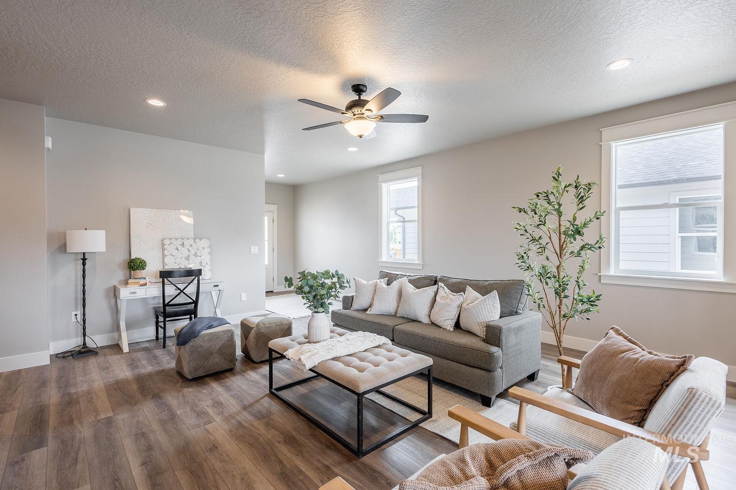 Spacious living area featuring wood-finish flooring, recessed lighting, and a ceiling fan with integrated light