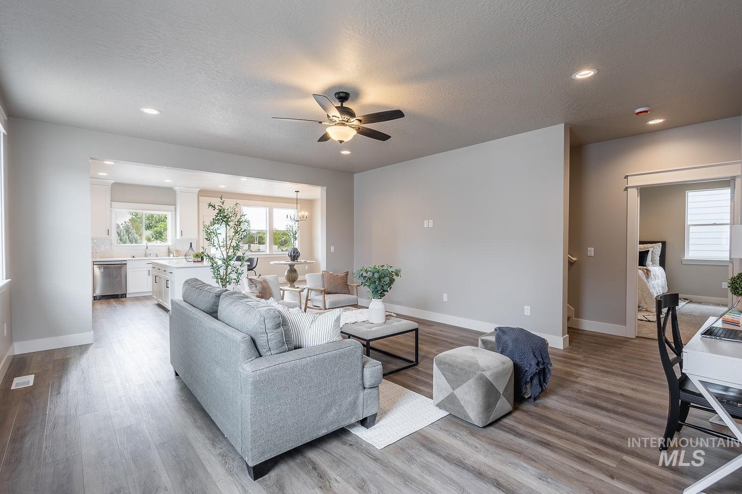 Spacious living area featuring wood-finish flooring, recessed lighting, and a ceiling fan