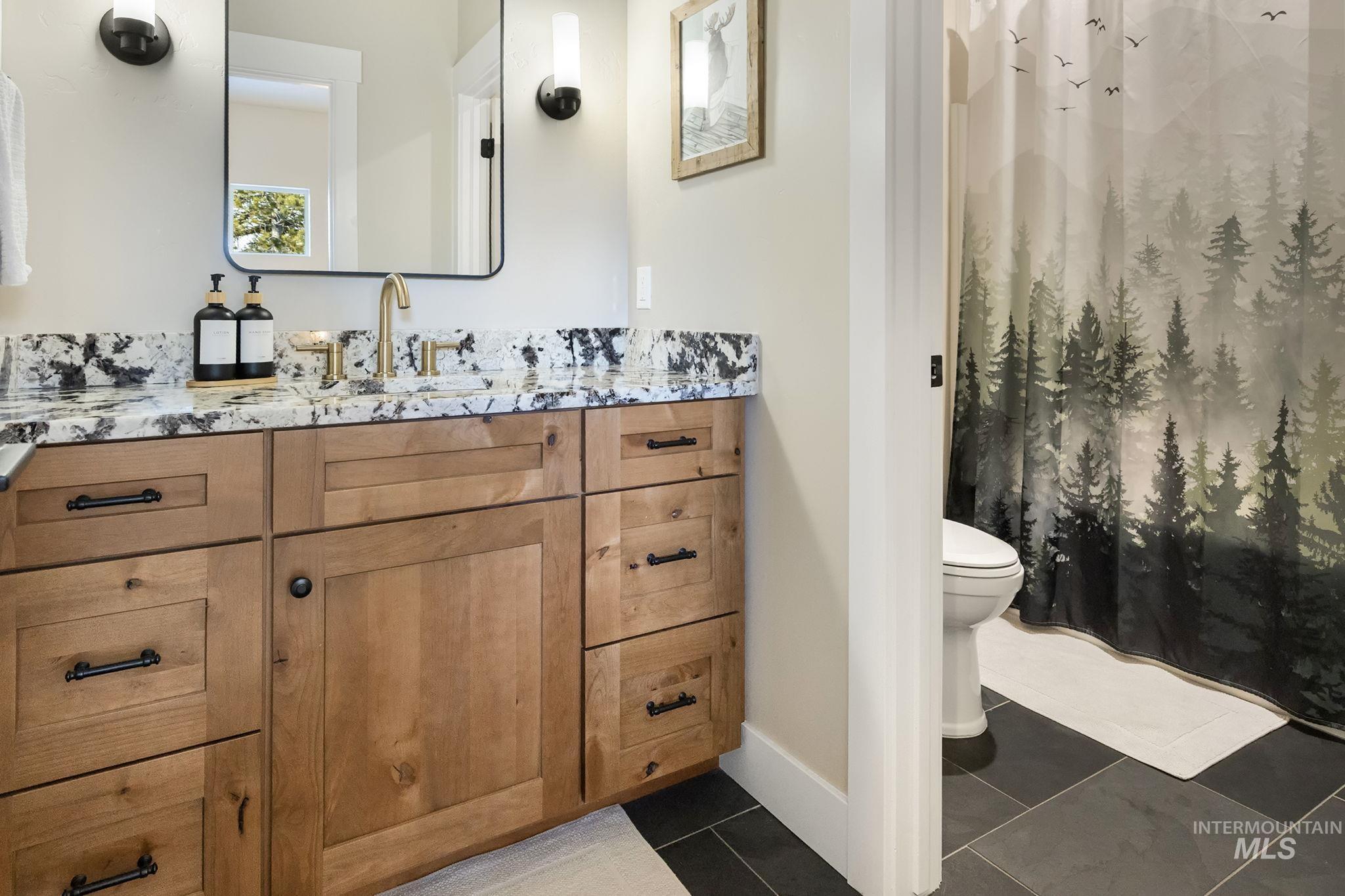 Bathroom featuring vanity and dark tile patterned floors