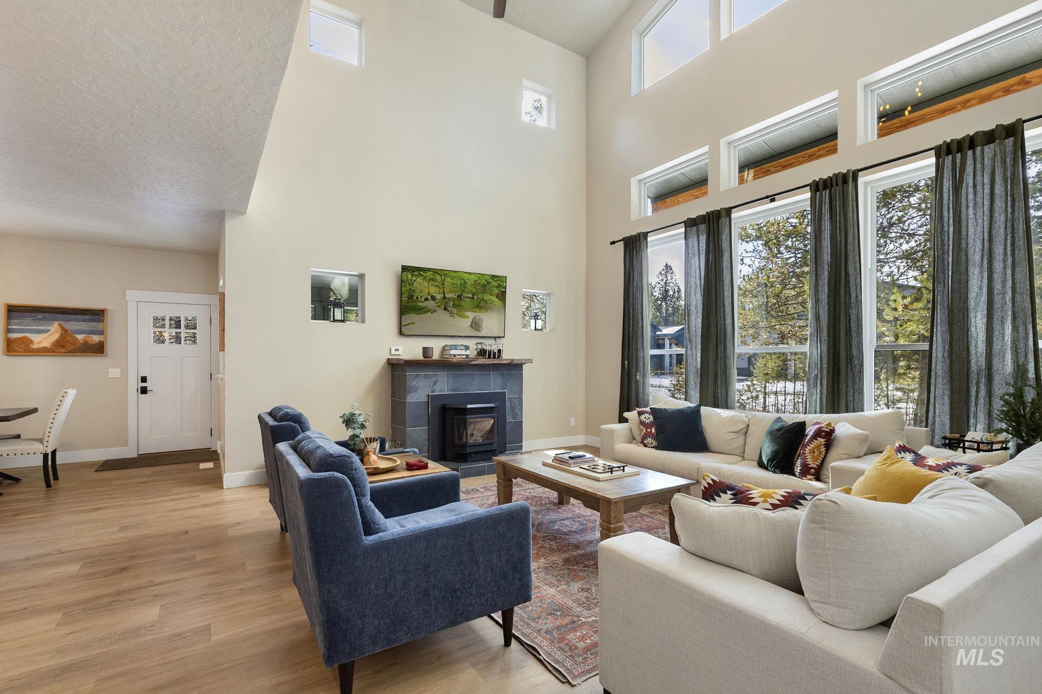 Living room with light wood finished floors, a tile fireplace, and a high ceiling