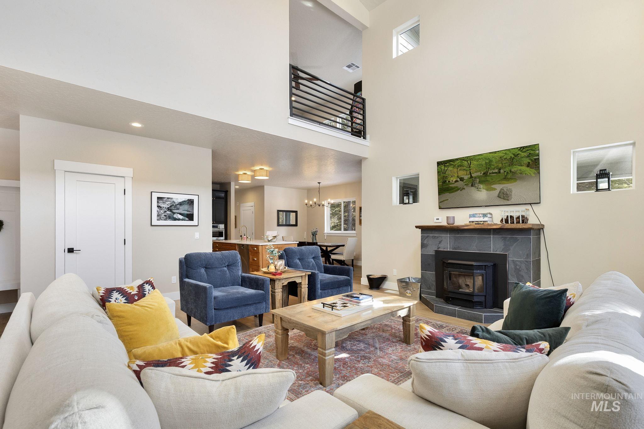 Living area with suspended lighting, a high ceiling, and wood finished floors