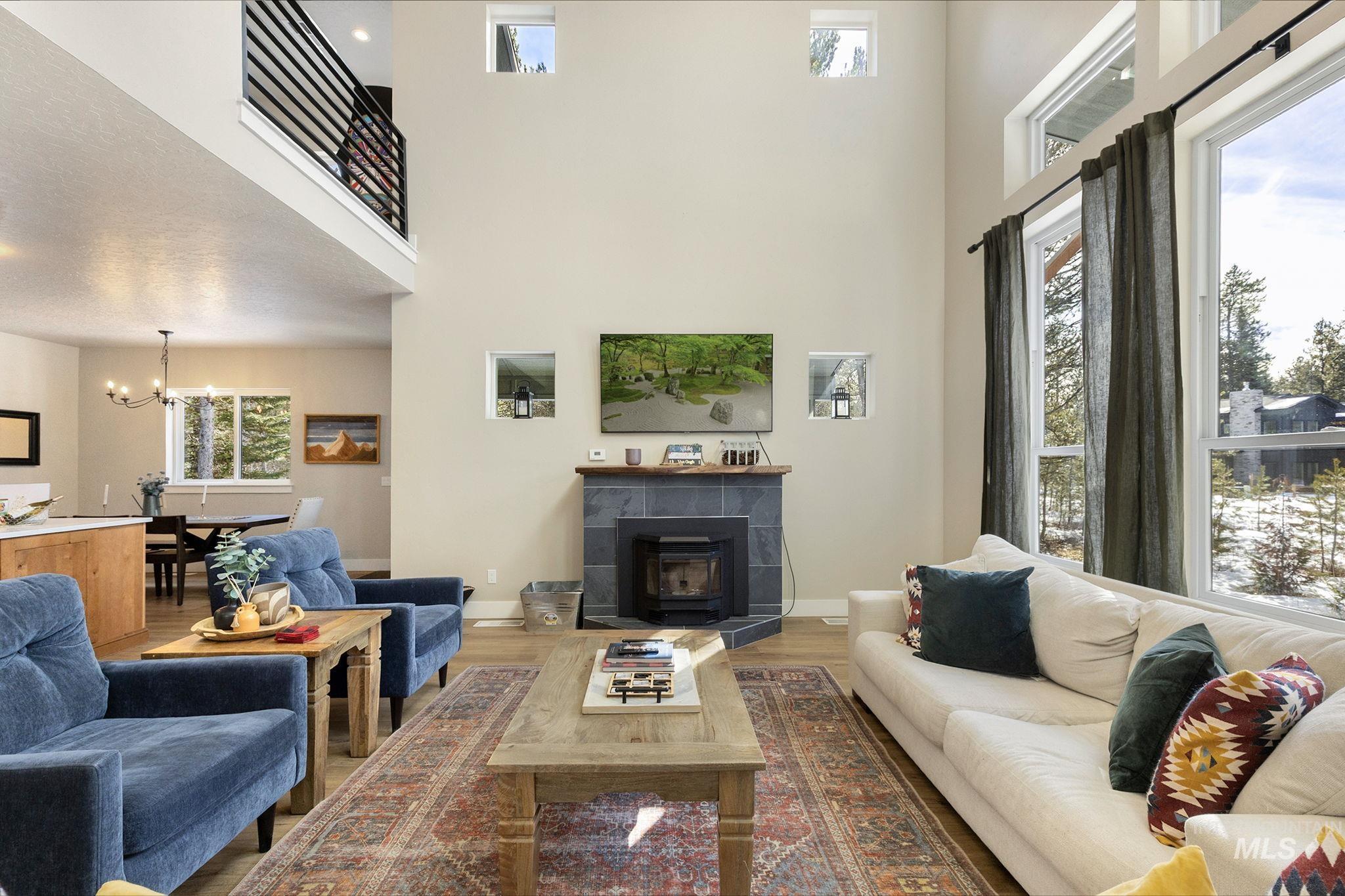 Living area featuring a fireplace, a chandelier, wood finished floors, and a high ceiling