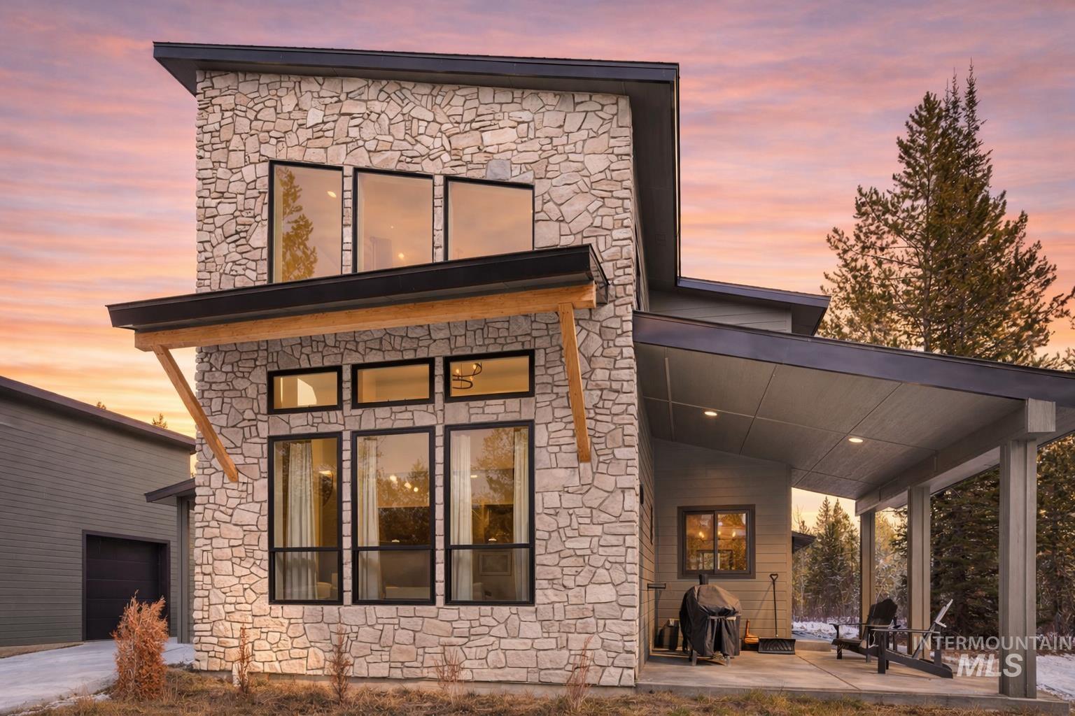 Back of house with stone siding and a patio