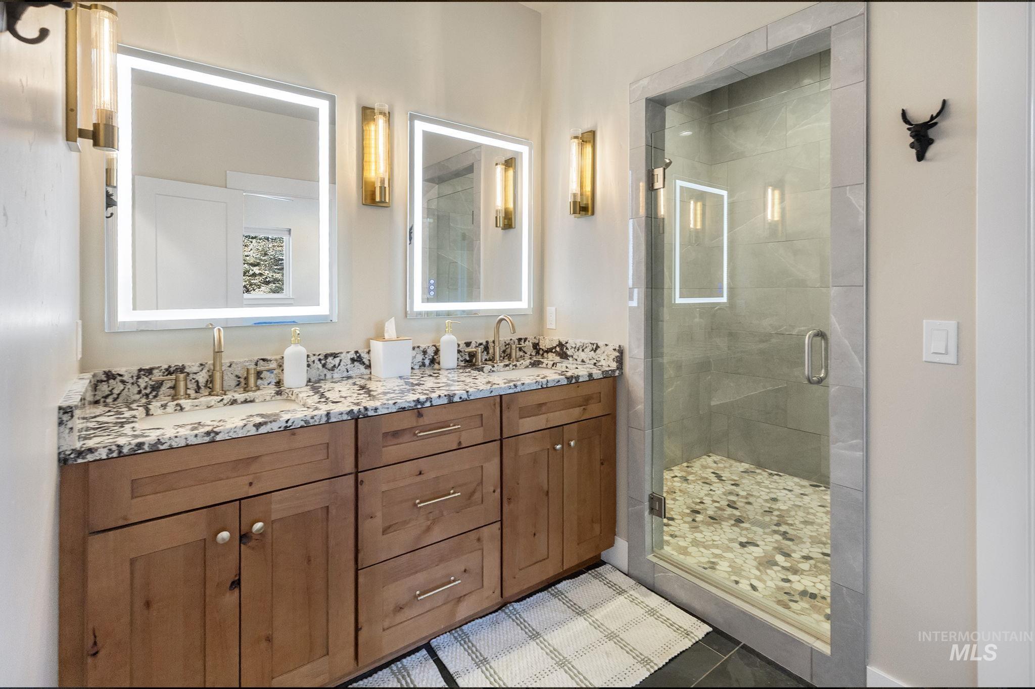 Full bathroom featuring a shower stall, double vanity, and tile patterned flooring