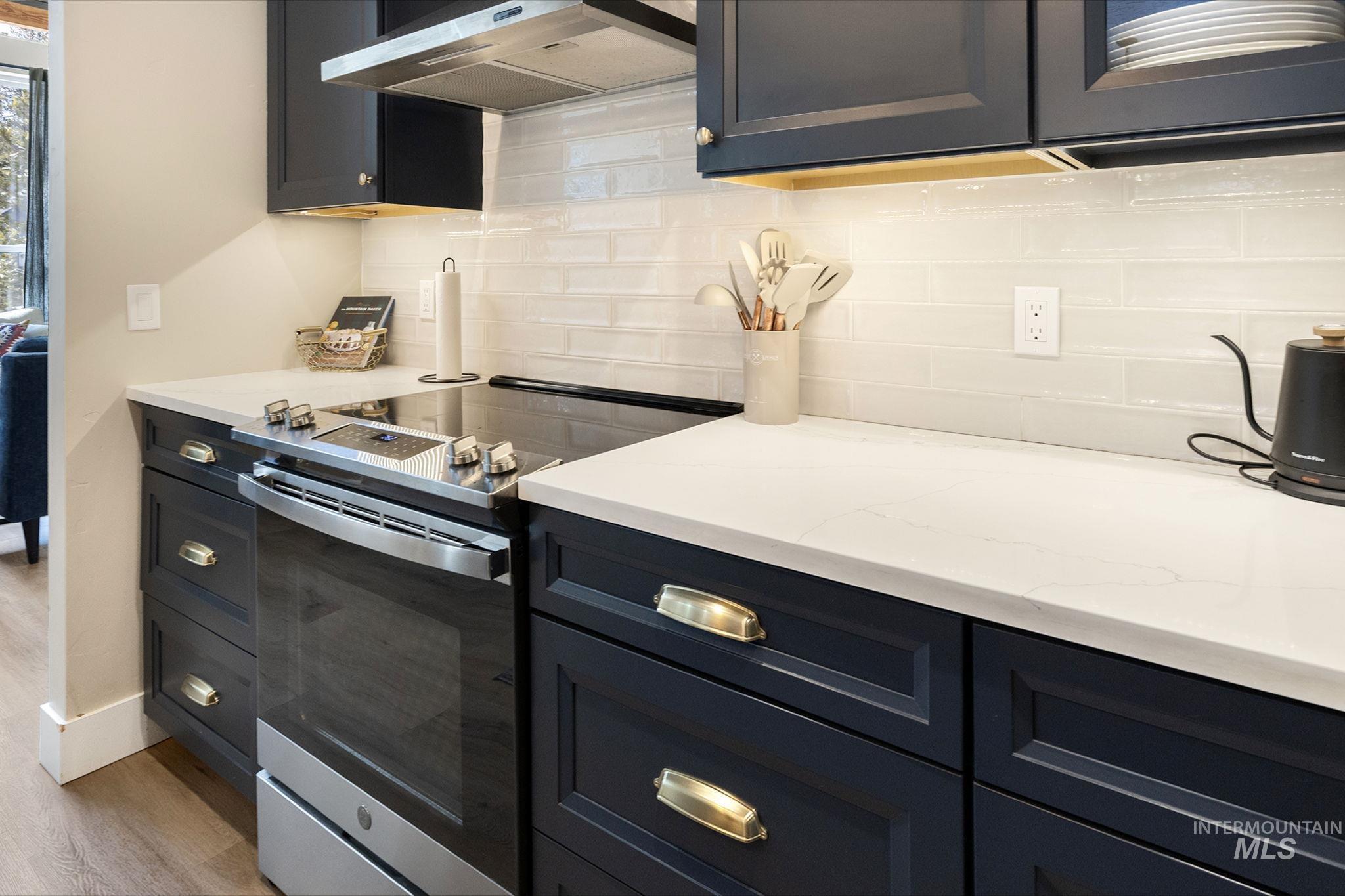 Kitchen with stainless steel range with electric stovetop, light stone countertops, tasteful backsplash, and light wood-style flooring