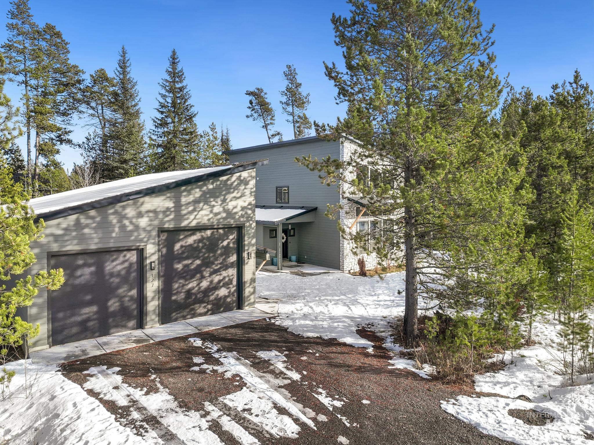 View of snow covered exterior with a garage and driveway