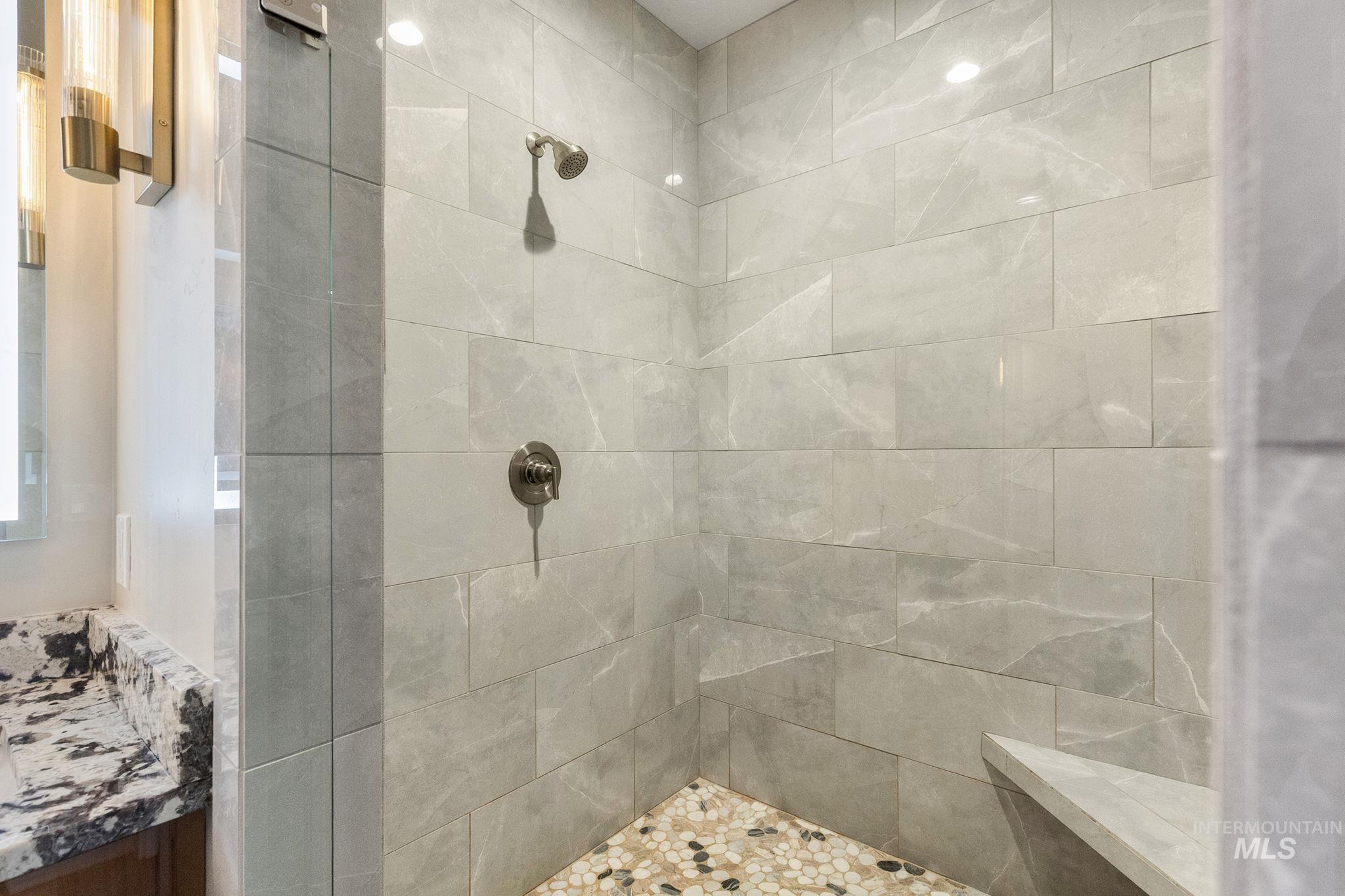Bathroom featuring tiled shower and vanity