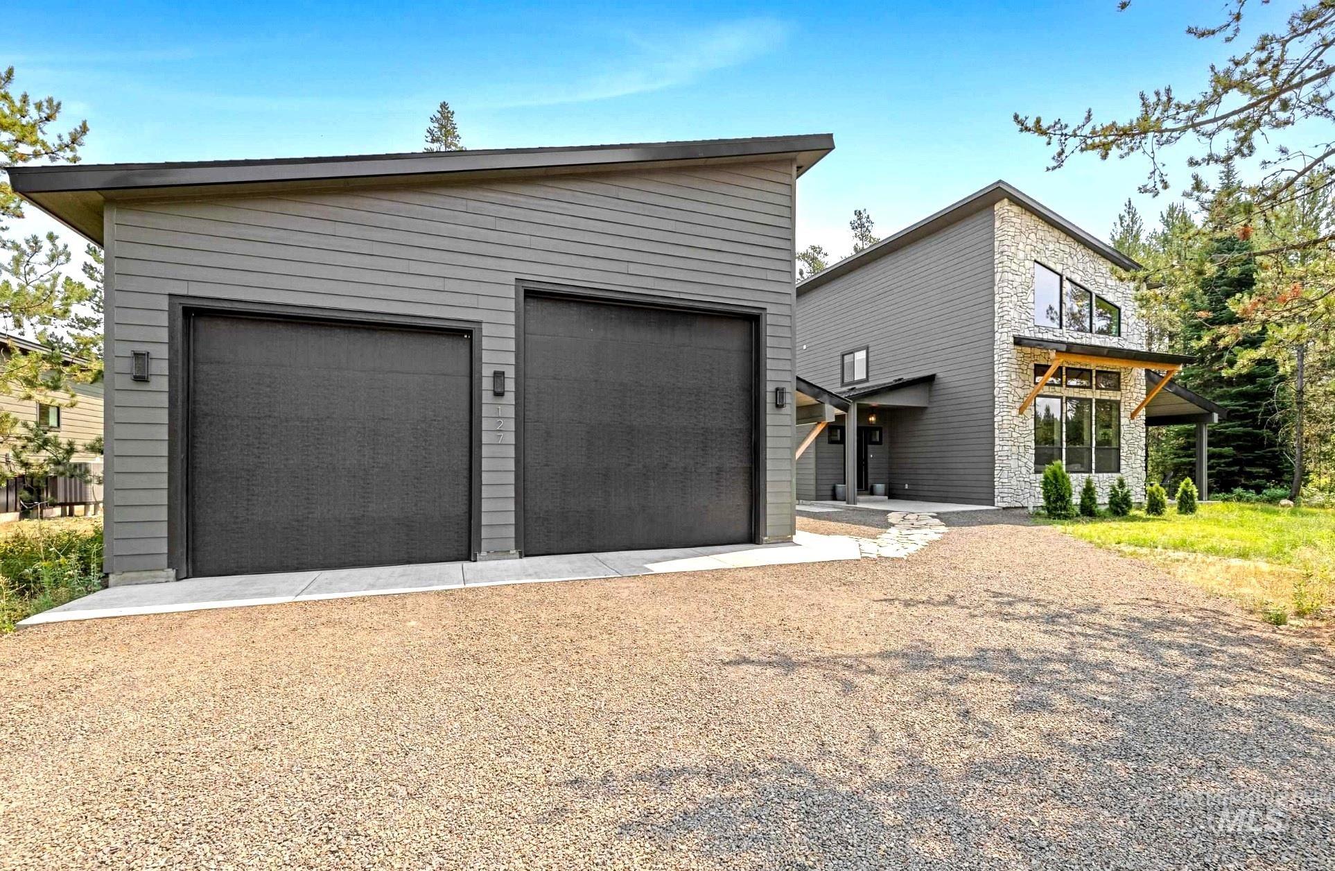 View of front facade featuring stone siding, an outbuilding, and a garage